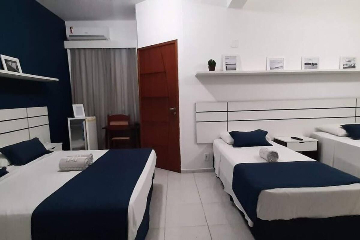 Habitación de hotel con dos camas individuales, un escritorio, una silla, una mesita y un armario.