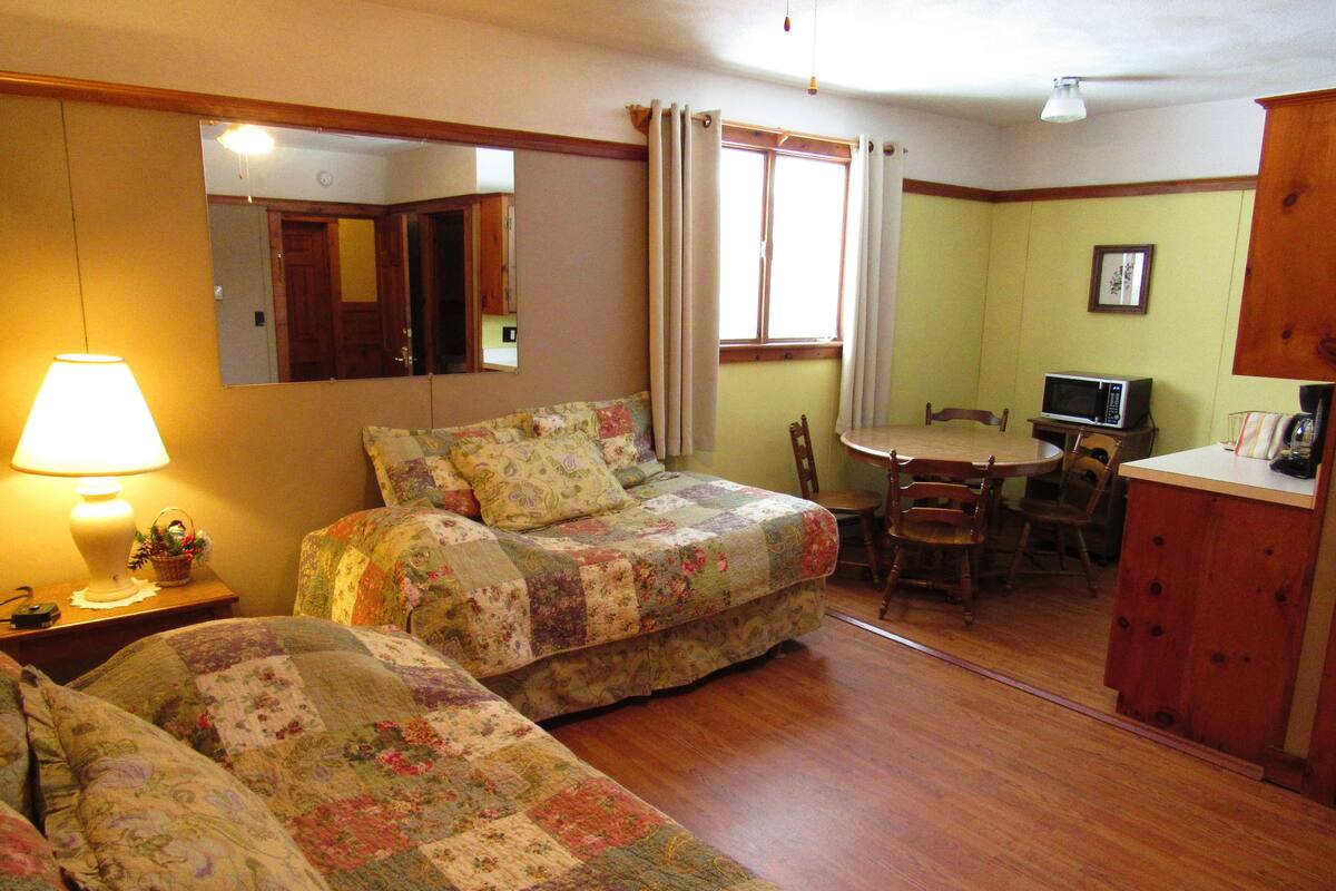 Um quarto aconchegante com duas camas, uma escrivaninha e uma cadeira.
