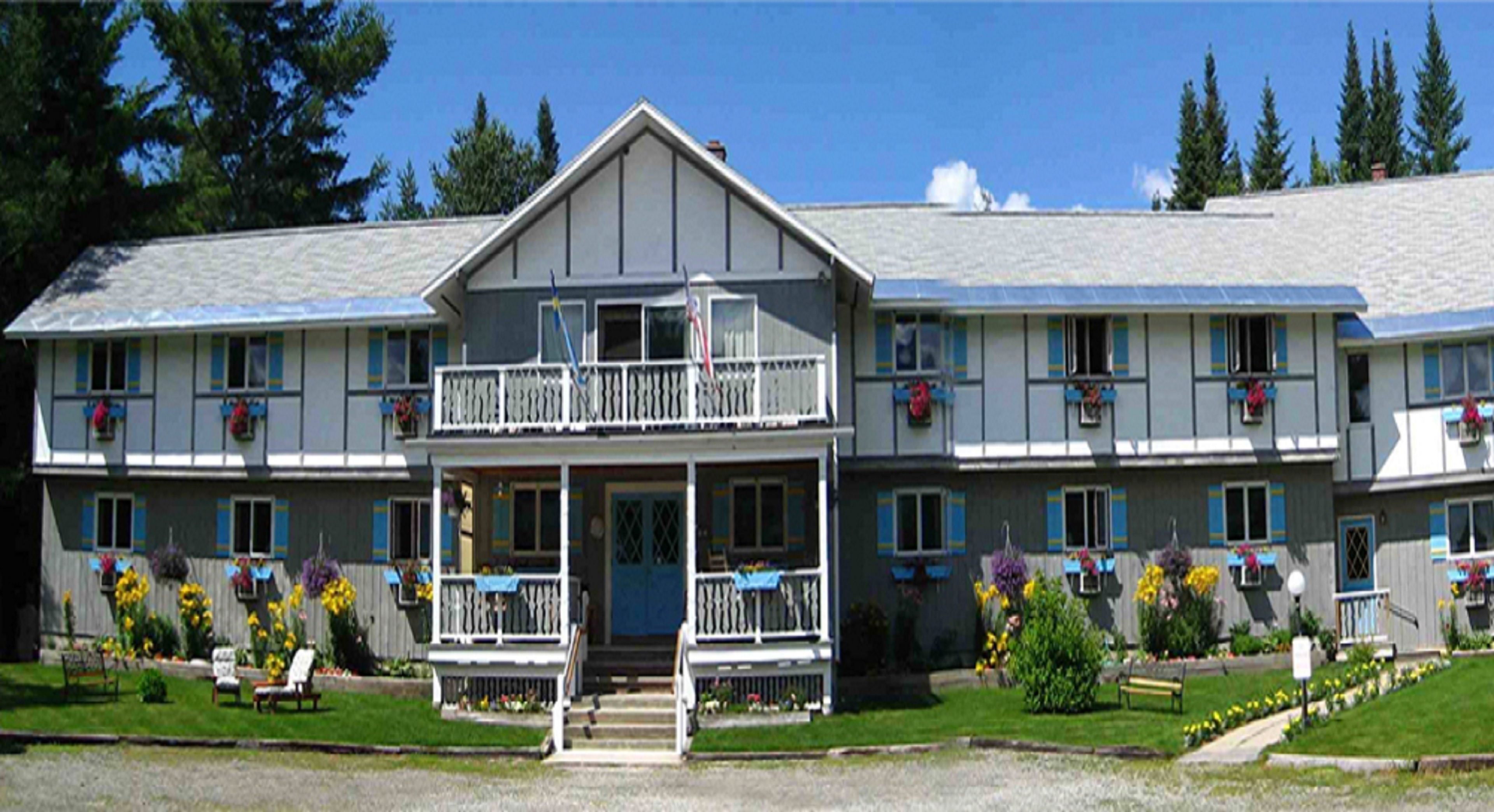 A two-story building with a balcony on the second floor, a front porch, and flower boxes on the windows.