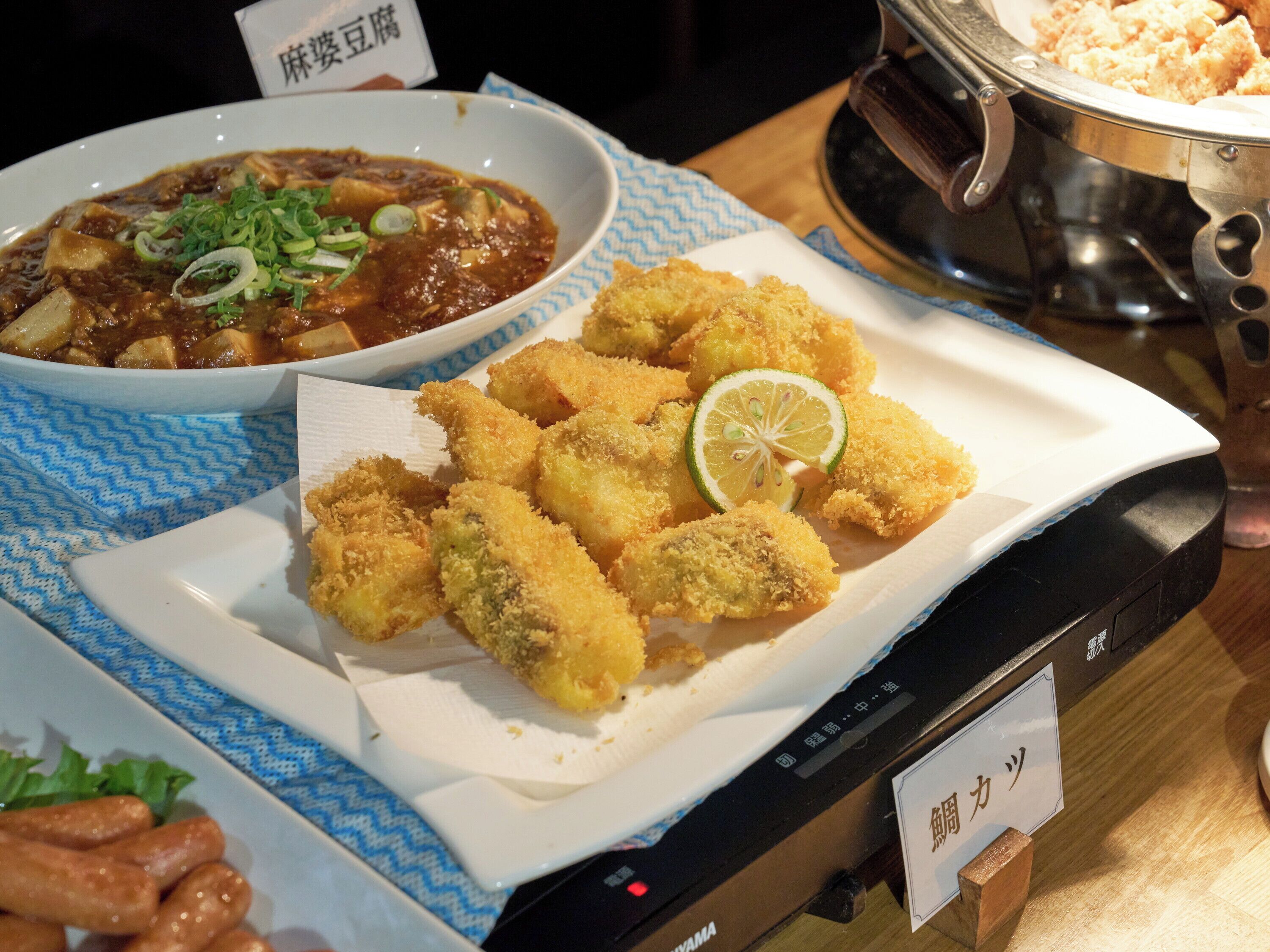 A table with a bowl of soup and breaded items, possibly fried food, on a blue patterned tablecloth.