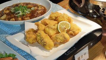 A table with a bowl of soup and breaded items, possibly fried food, on a blue patterned tablecloth.