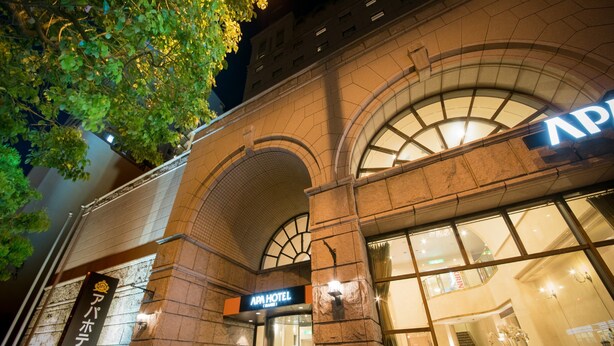 A hotel entrance with a large arched window and a sign reading "APM HOTEL".