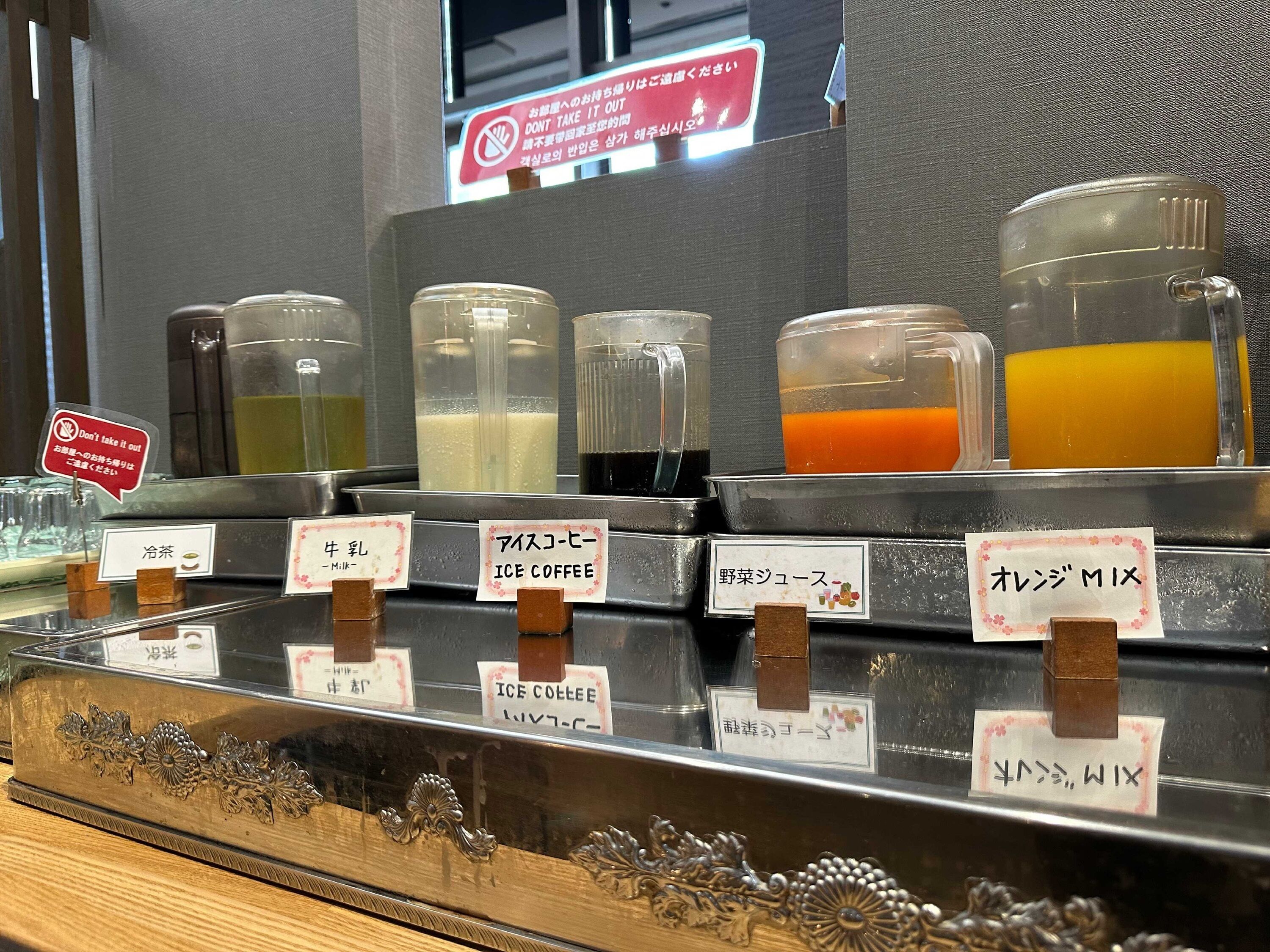 A beverage dispenser with various drinks labeled in Japanese, including iced coffee and a mix.