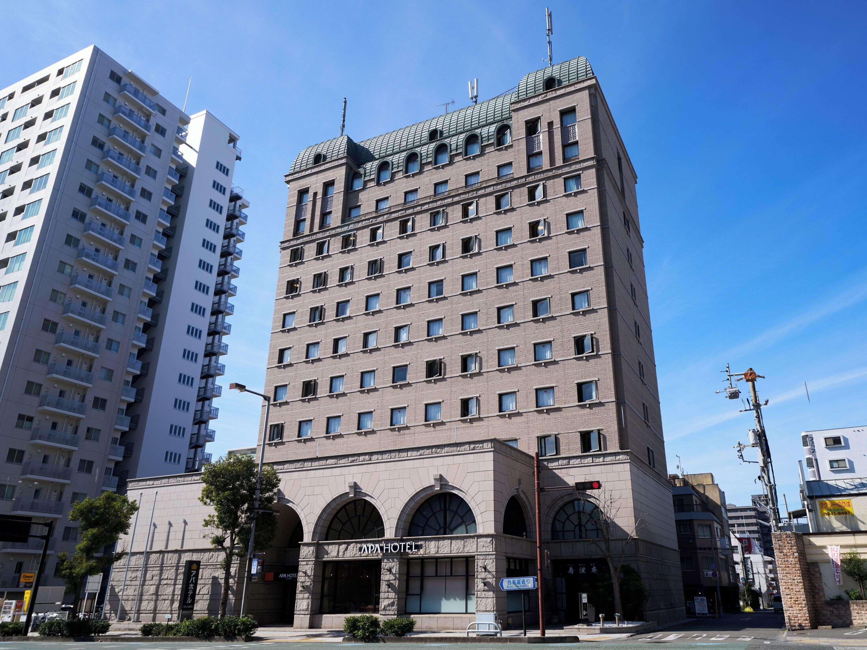 Un hotel de varios pisos con un estilo arquitectónico clásico, que presenta una entrada destacada con ventanas arqueadas y un letrero que dice 