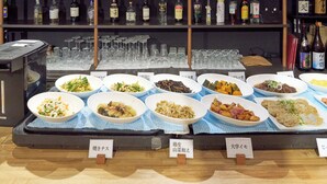 A buffet with various dishes and a selection of liquor bottles in the background.