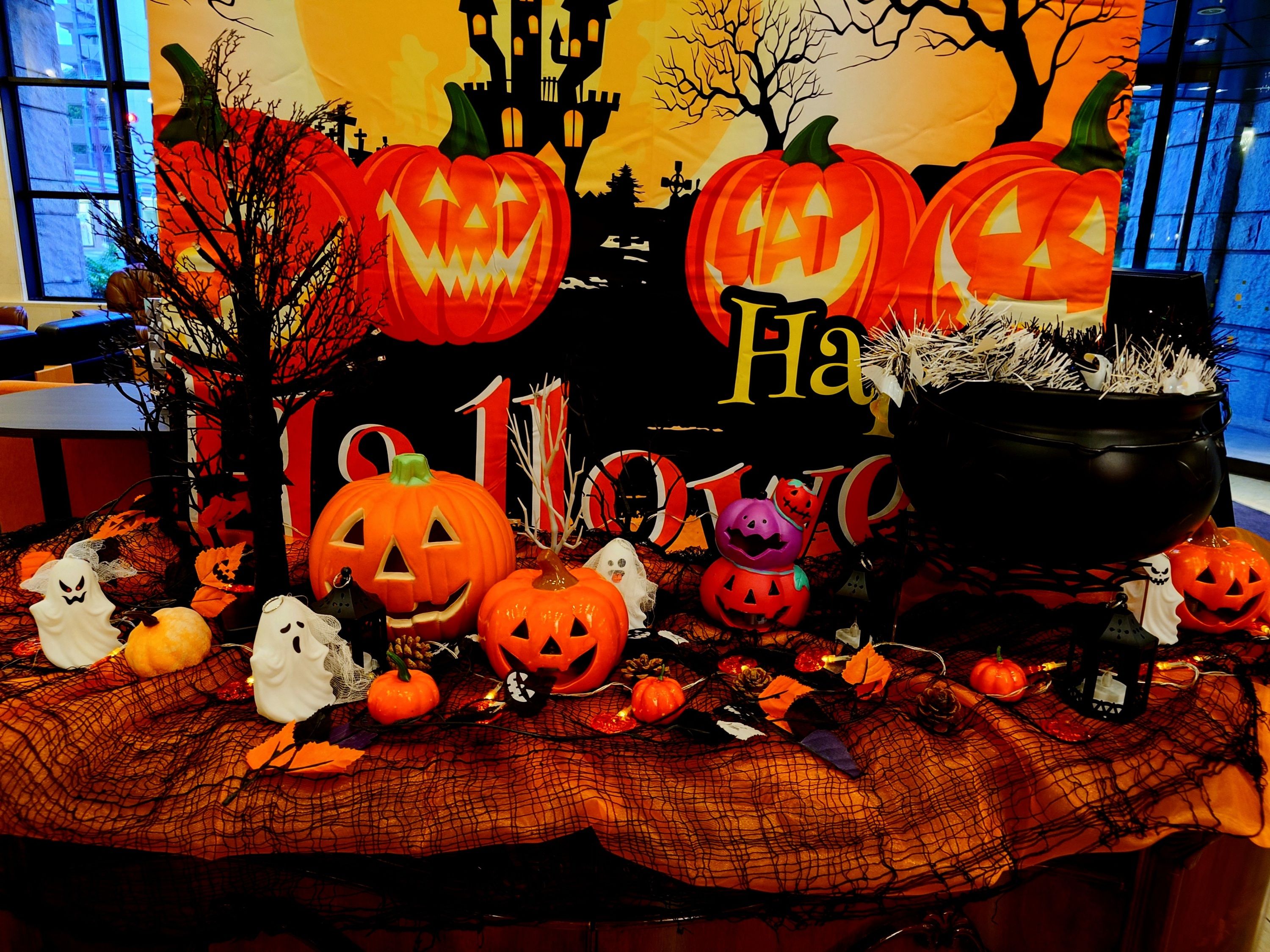 Decoración temática de Halloween con calabazas talladas, figuras de fantasmas y un caldero.