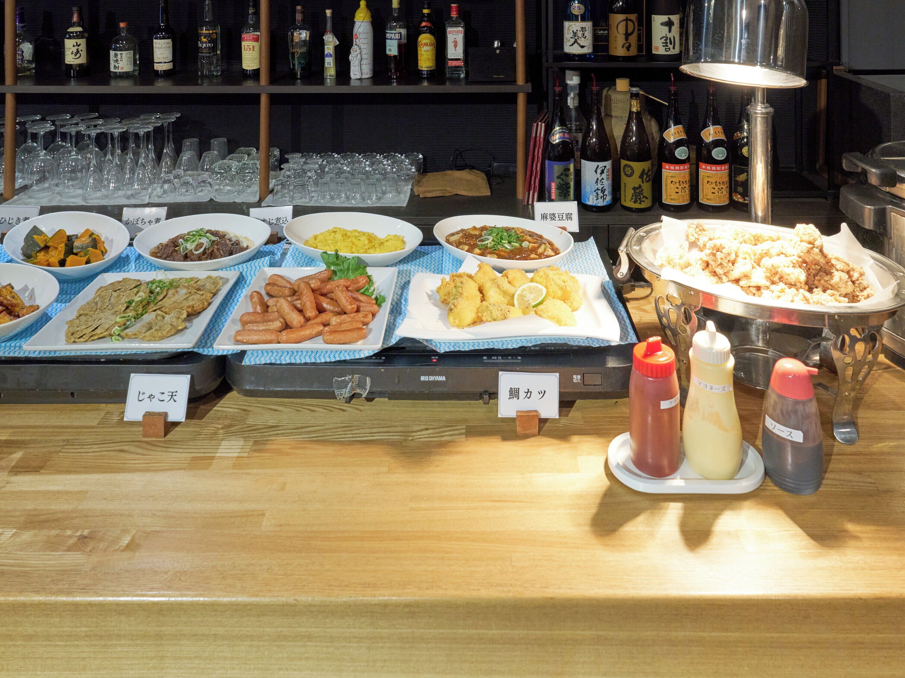 Een buffet met diverse gerechten, sauzen en een assortiment alcoholische dranken.
