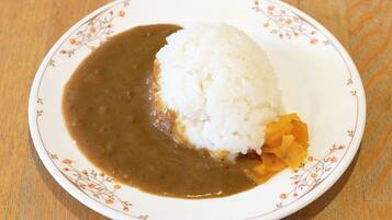 A plate with white rice and a brown sauce, possibly curry, on a floral-patterned plate.