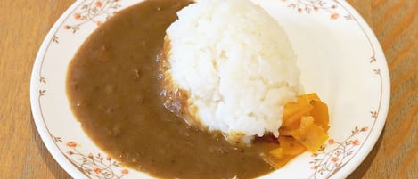 A plate with white rice and a brown sauce, possibly curry, on a floral-patterned plate.