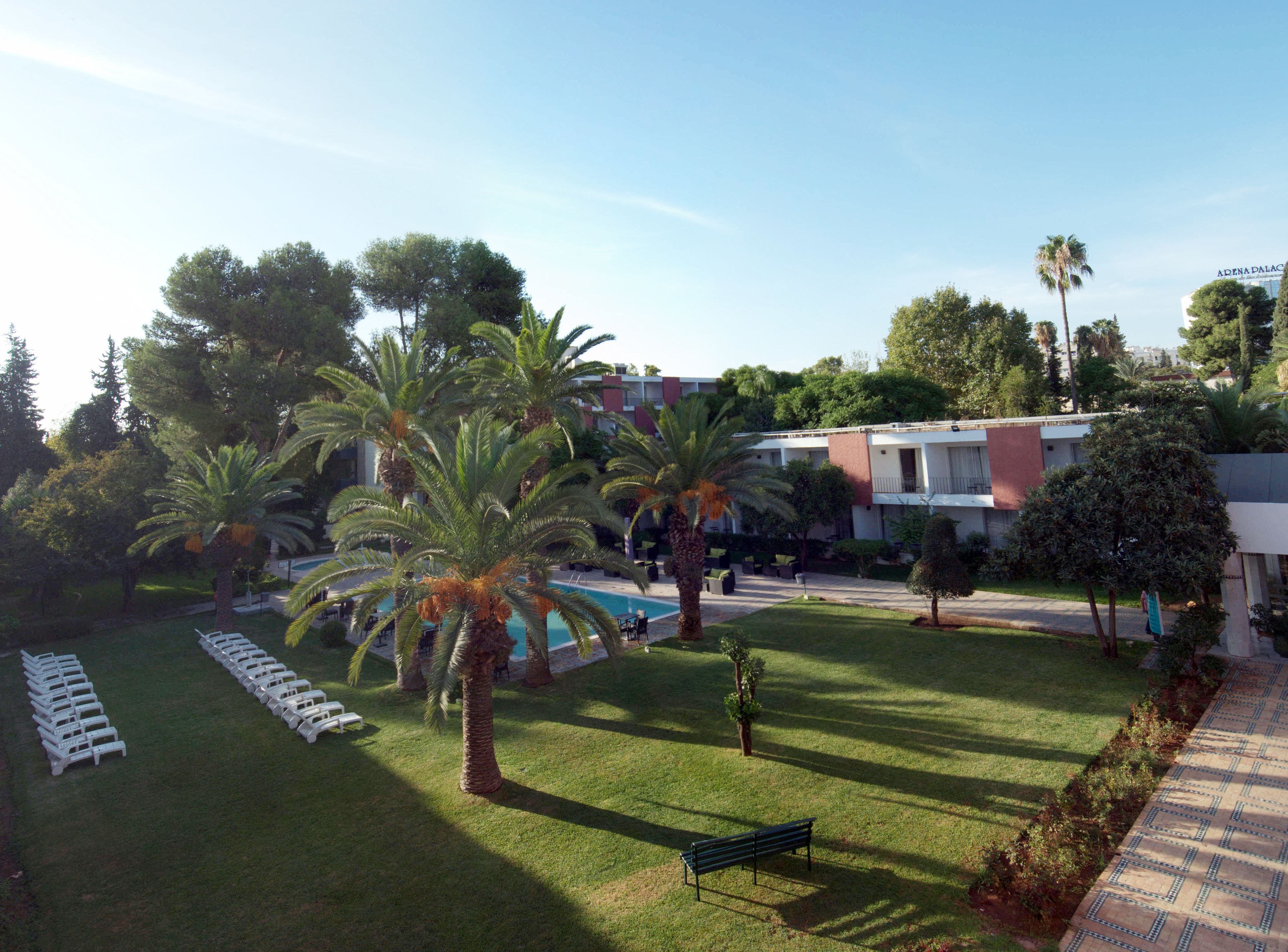 A hotel courtyard with a pool, palm trees, and lounge chairs.