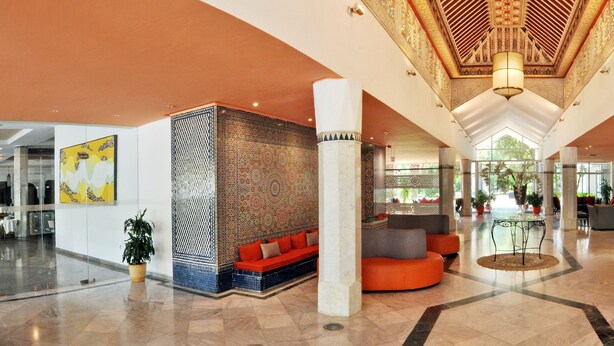 A spacious lobby with a high ceiling, patterned walls, and a reception desk. - Hôtel Volubilis (Fes)