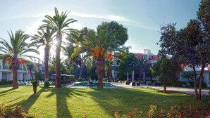 A hotel courtyard with a swimming pool, palm trees, and a tiled walkway. - Hôtel Volubilis (Fes)