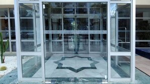A modern building entrance with glass doors and a star-shaped floor design. - Hôtel Volubilis (Fes)