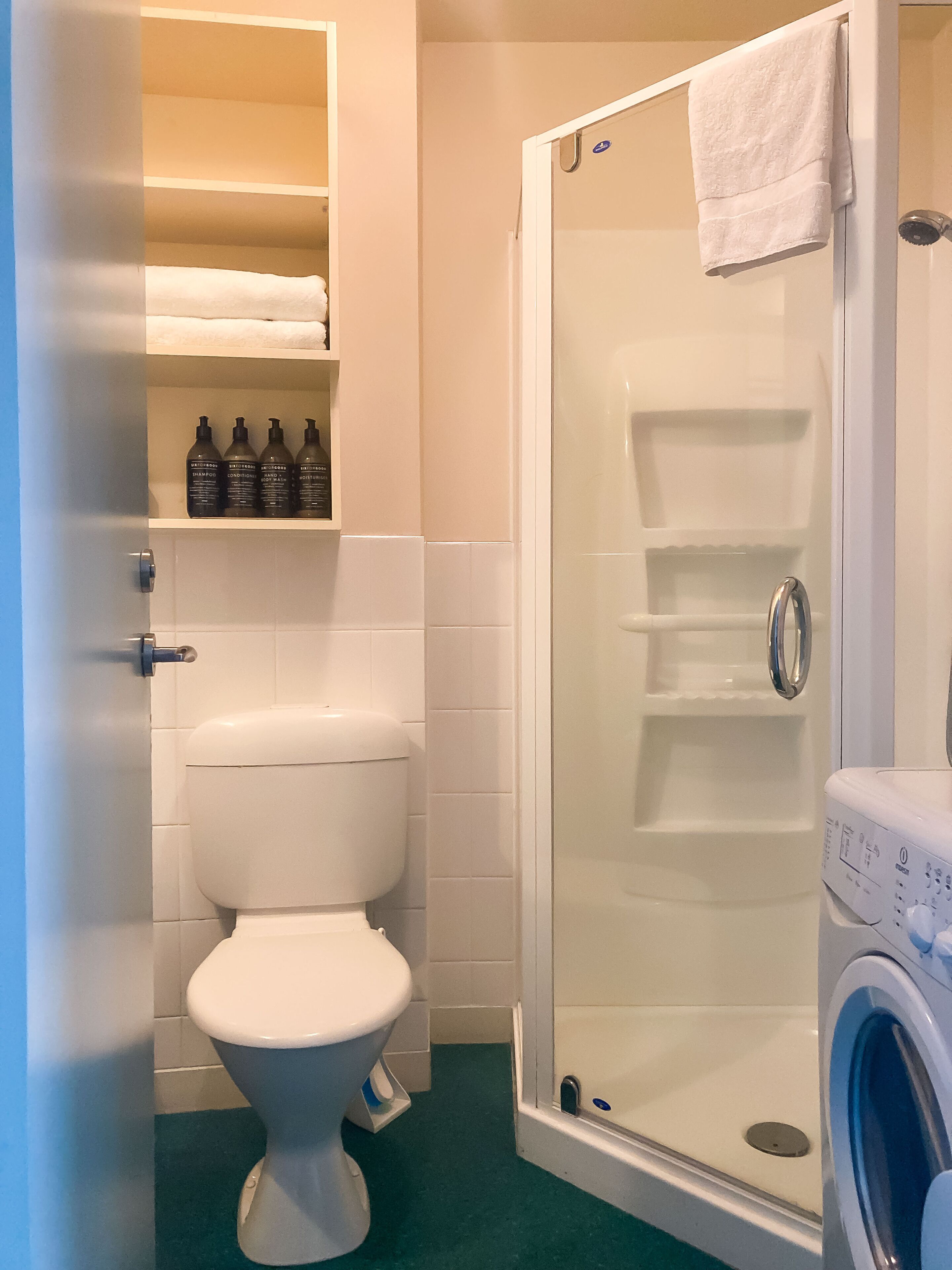 Een badkamer met toilet, een douchecabine en een wasmachine.