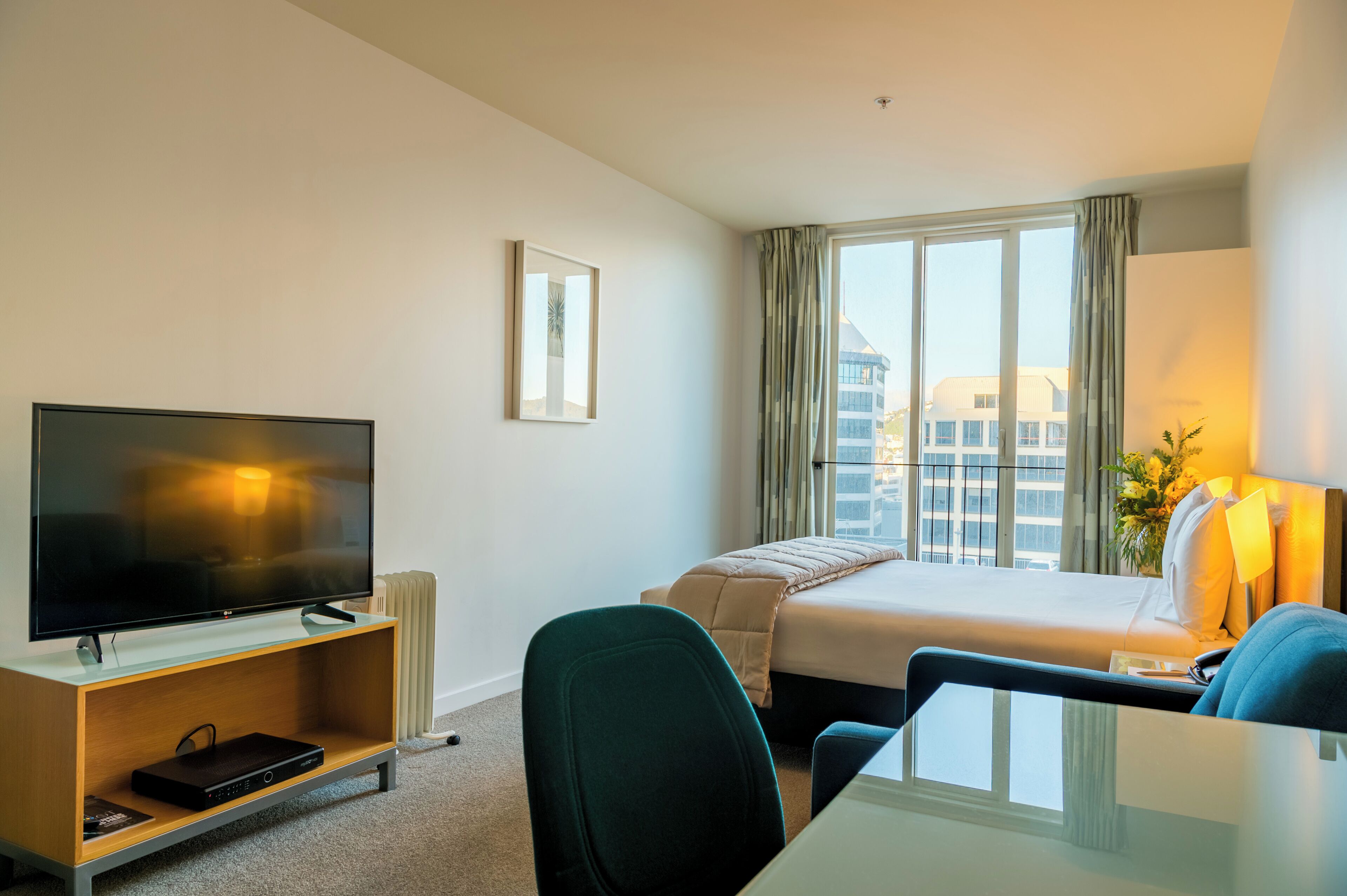 A hotel room with a bed, a TV, a desk, and a chair.