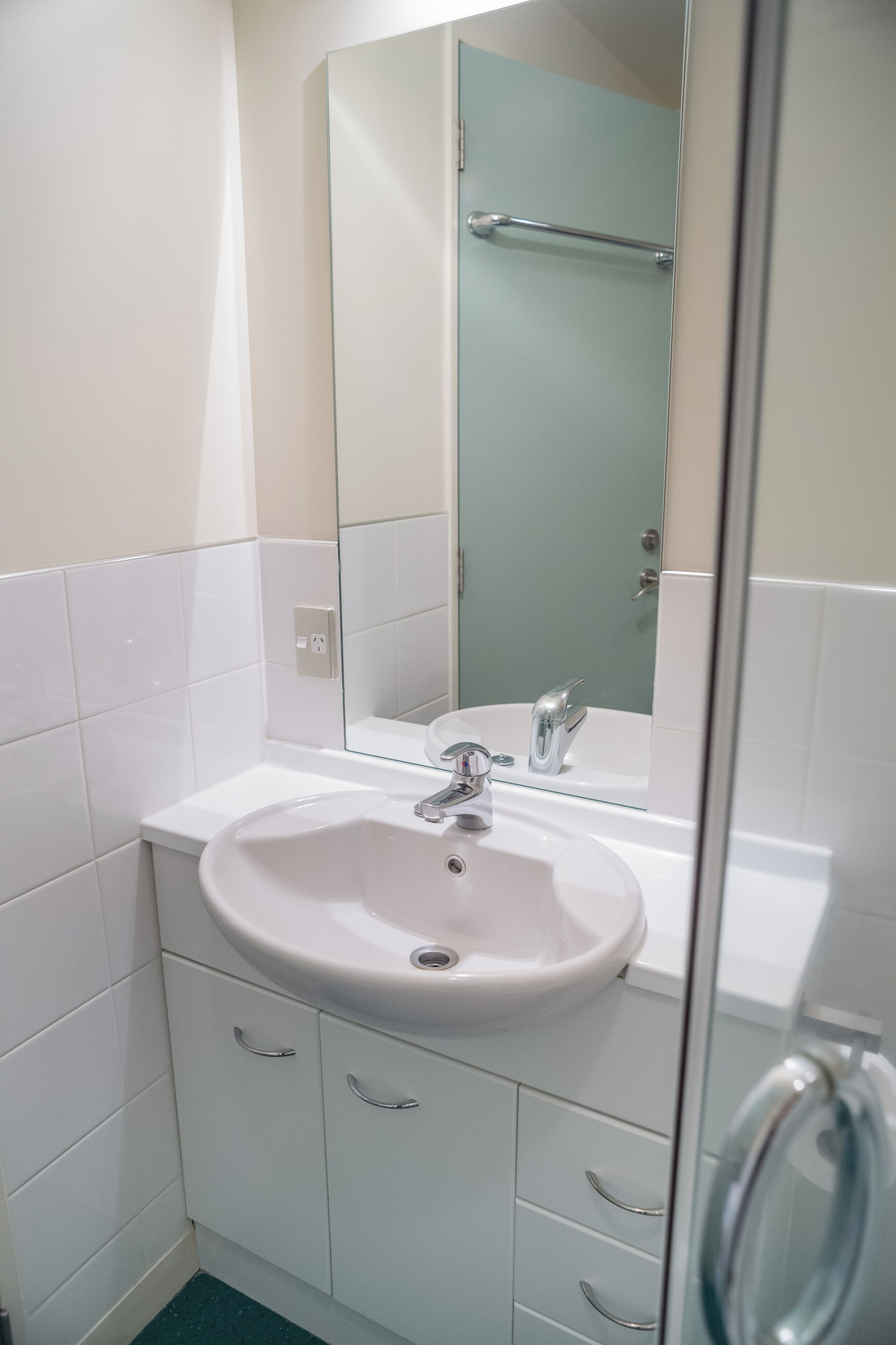 A bathroom with a white sink, a mirror, and a glass shower enclosure.