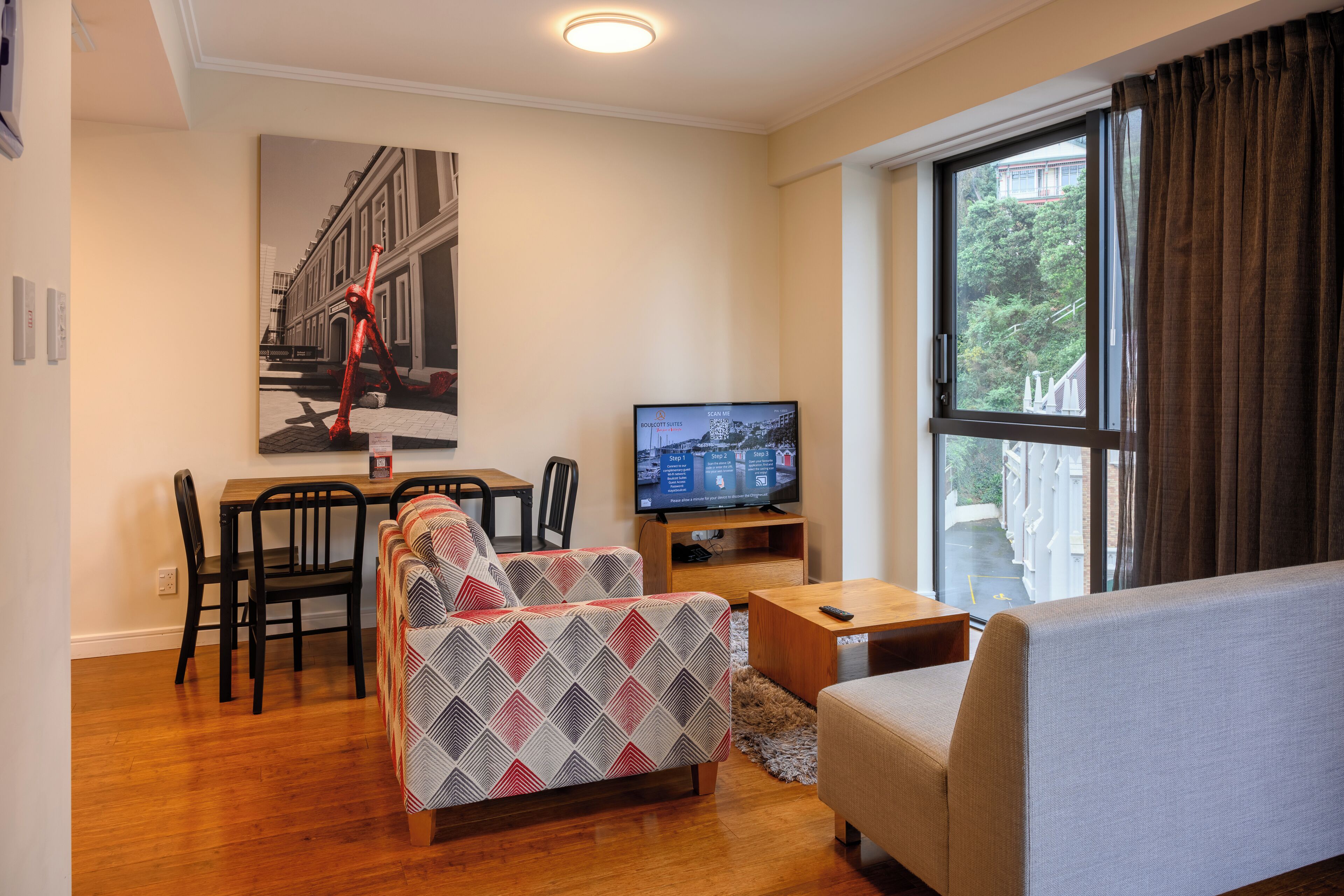 A modern living room with a sofa, a dining table with chairs, a TV, and a large window with curtains.