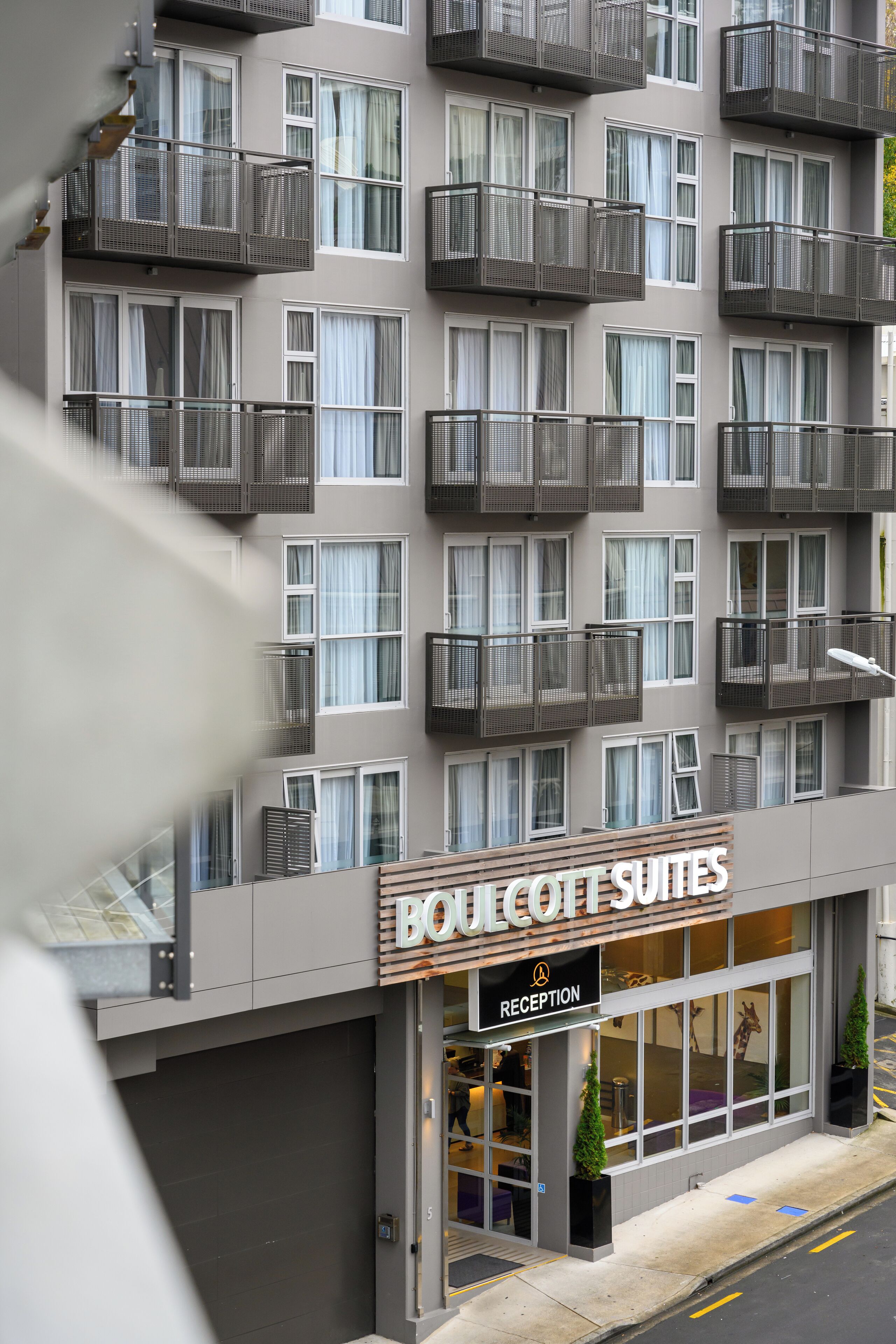 A hotel with multiple balconies, a reception area, and a sign indicating it is a Boulanger Suites hotel.