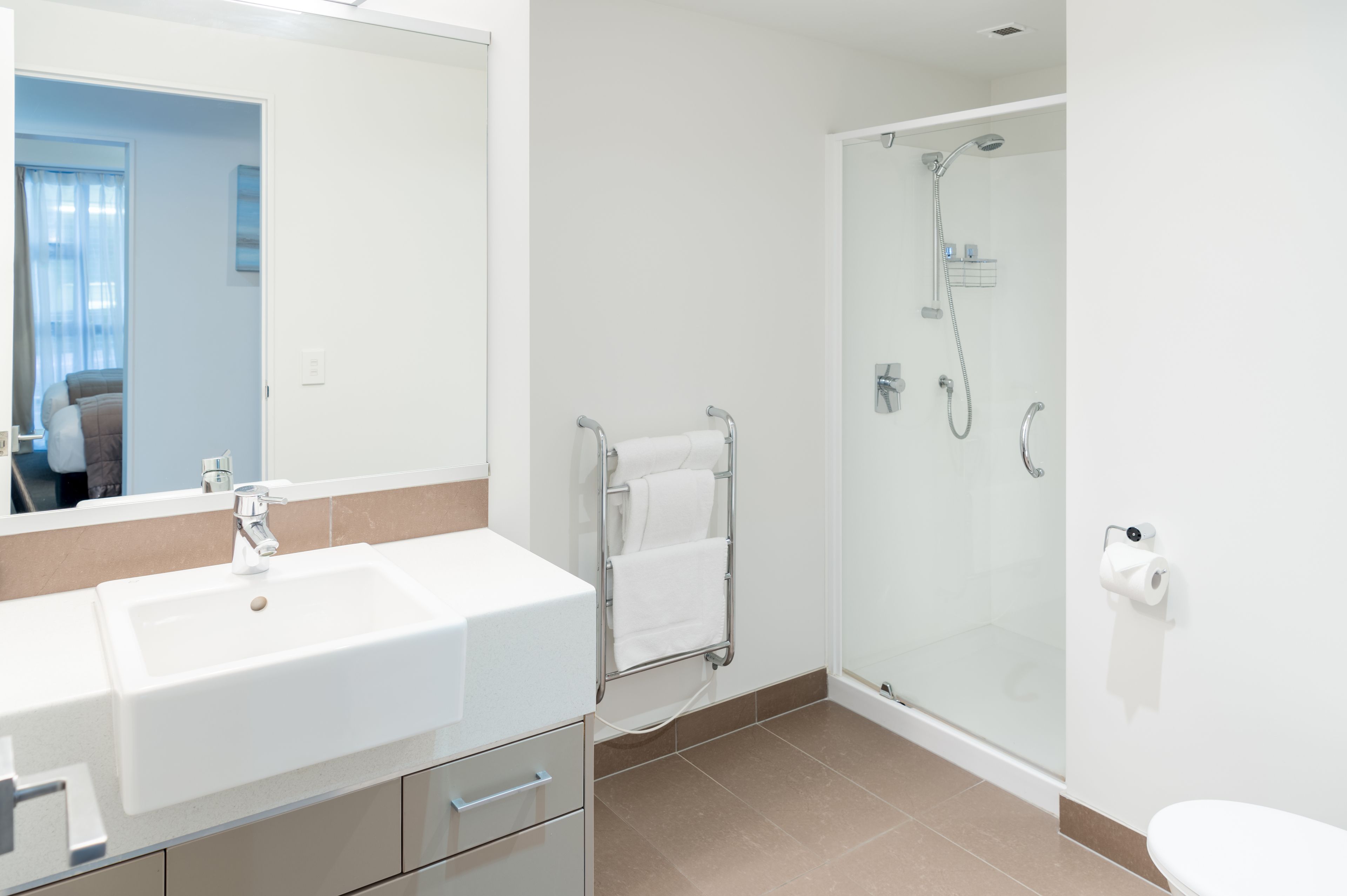 Une salle de bain moderne avec un lavabo blanc, une douche en verre et des toilettes.