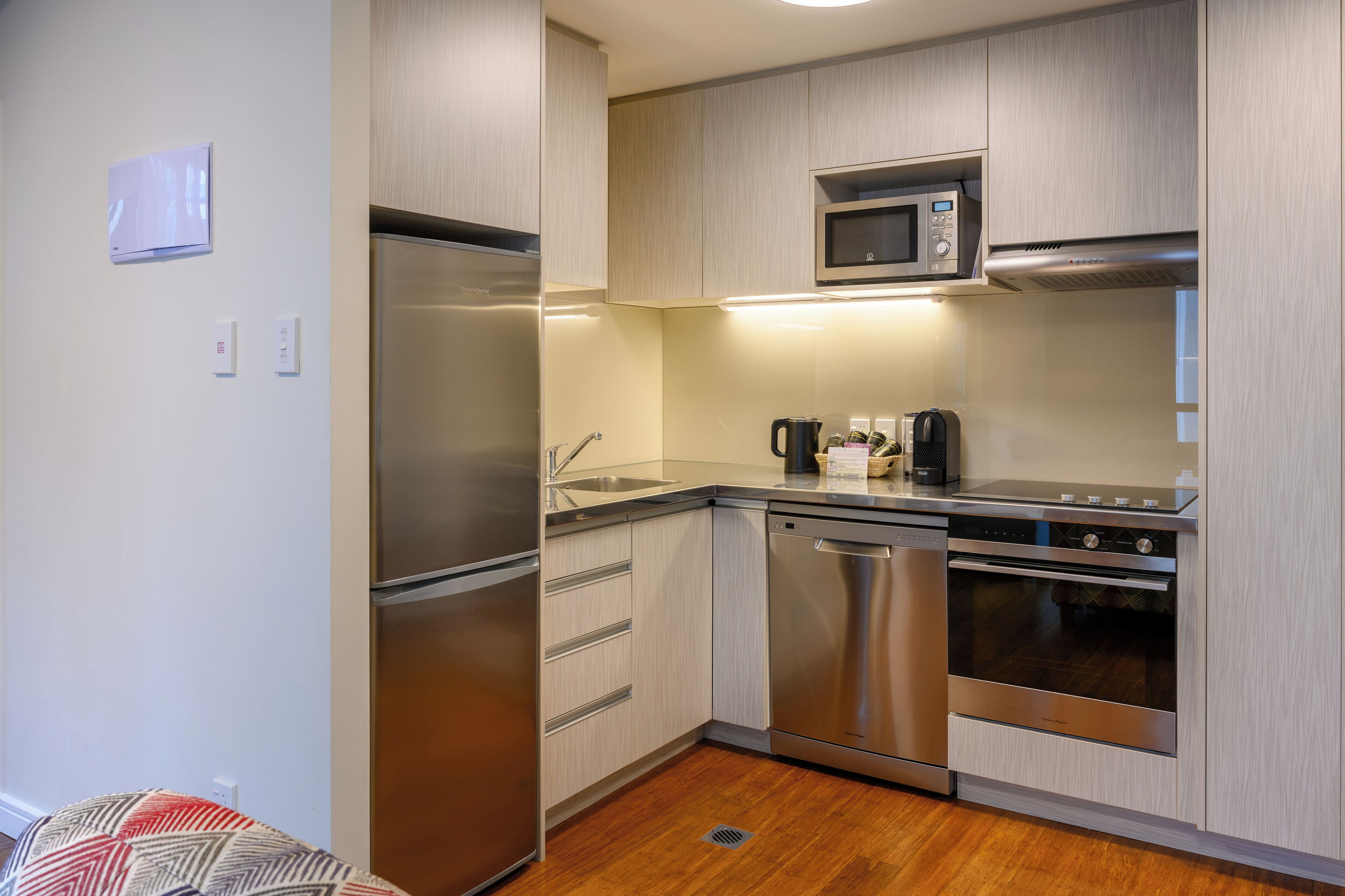 A modern kitchen with stainless steel appliances, wooden cabinets, and a built-in microwave.