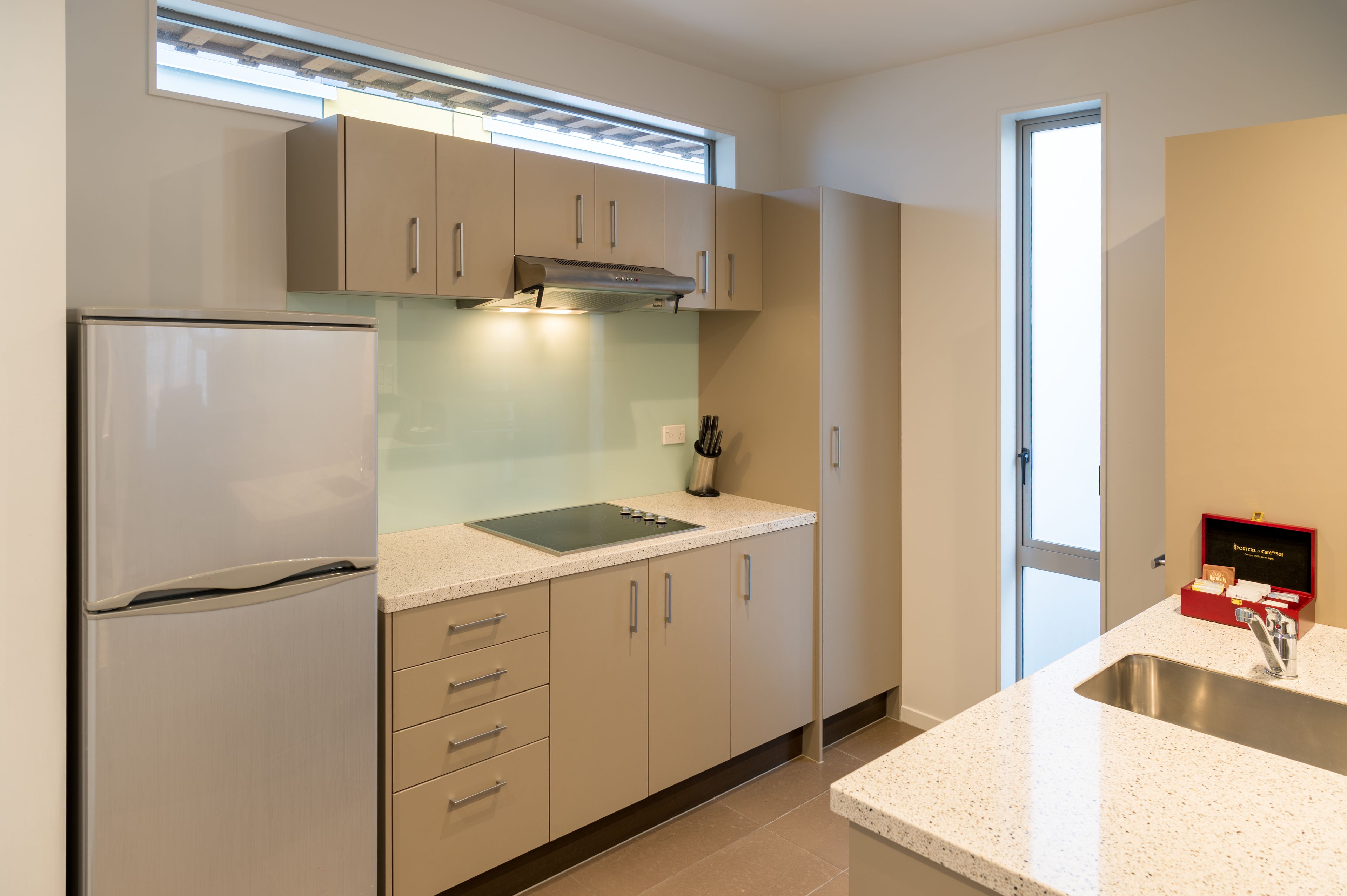 A modern kitchen with a stainless steel refrigerator, a built-in oven, and a double sink.