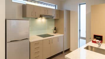 A modern kitchen with a stainless steel refrigerator, a built-in oven, and a double sink.
