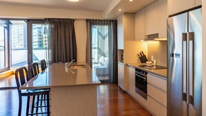 A modern kitchen with a central island, stainless steel appliances, and large windows with curtains. - Boulcott Suites (Wellington)