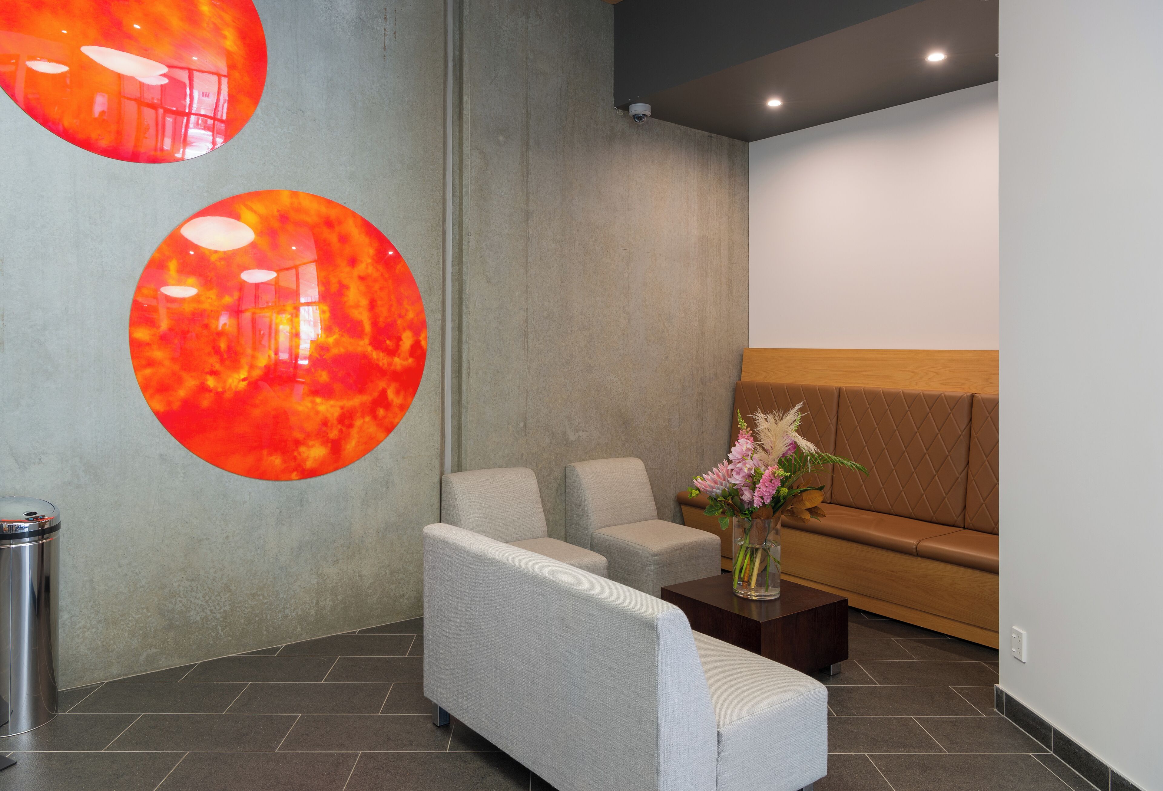 Een moderne lobby met een zithoek, een prullenbak en een decoratieve wand.