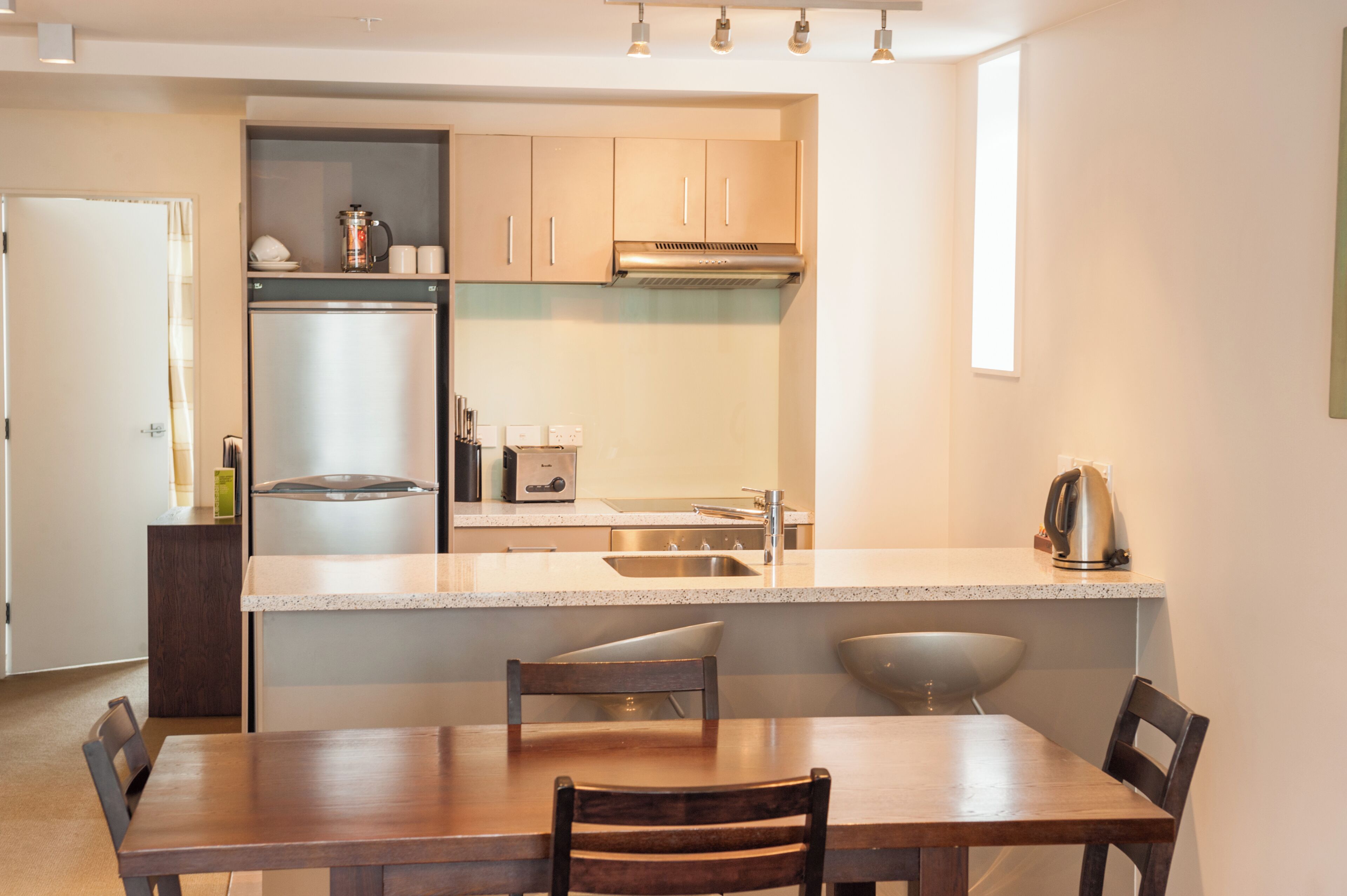 A modern kitchen with a central island, stainless steel appliances, and a dining area with a wooden table and chairs.