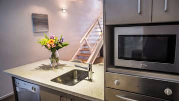 Una cocina con lavavajillas de acero inoxidable, horno empotrado y encimera de granito.