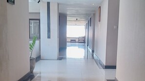 A long, well-lit corridor with a tiled floor, leading to a bright room. - Nirmala Hotel and Convention Centre (Denpasar)