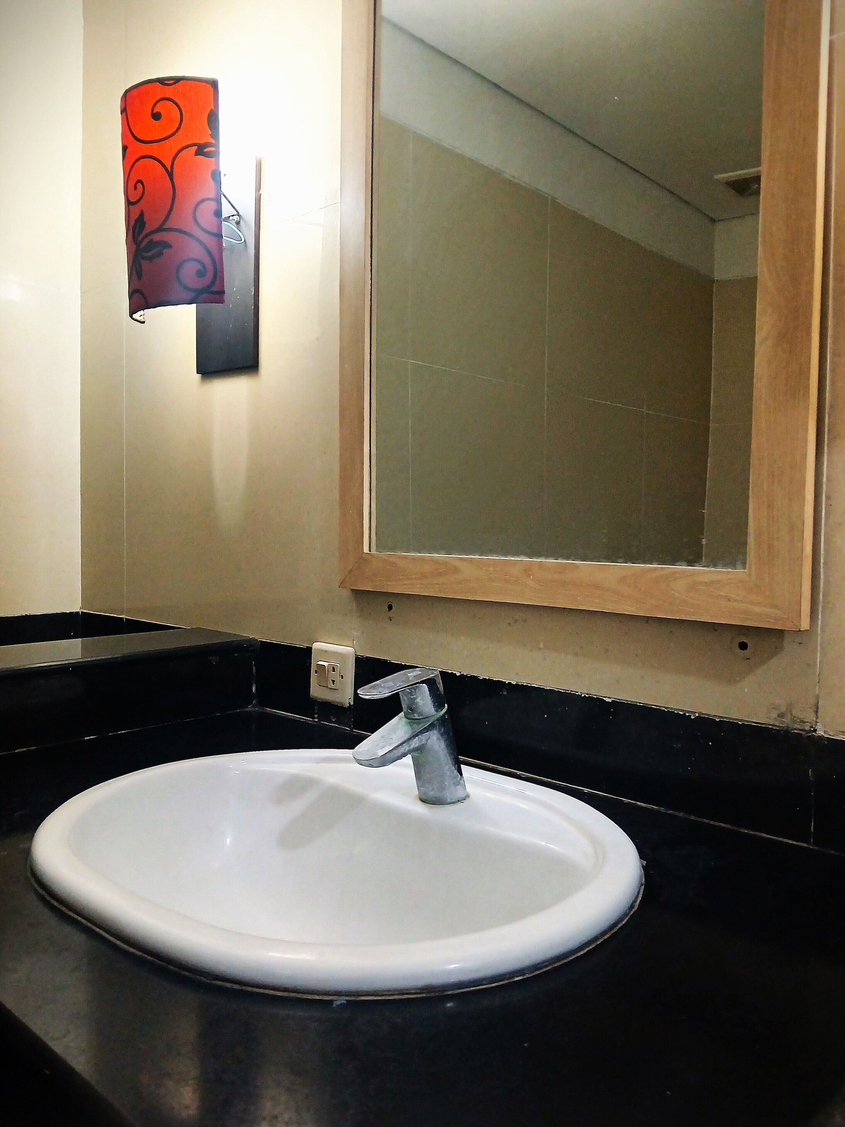 A bathroom with a white sink, a mirror, and a decorative light fixture.