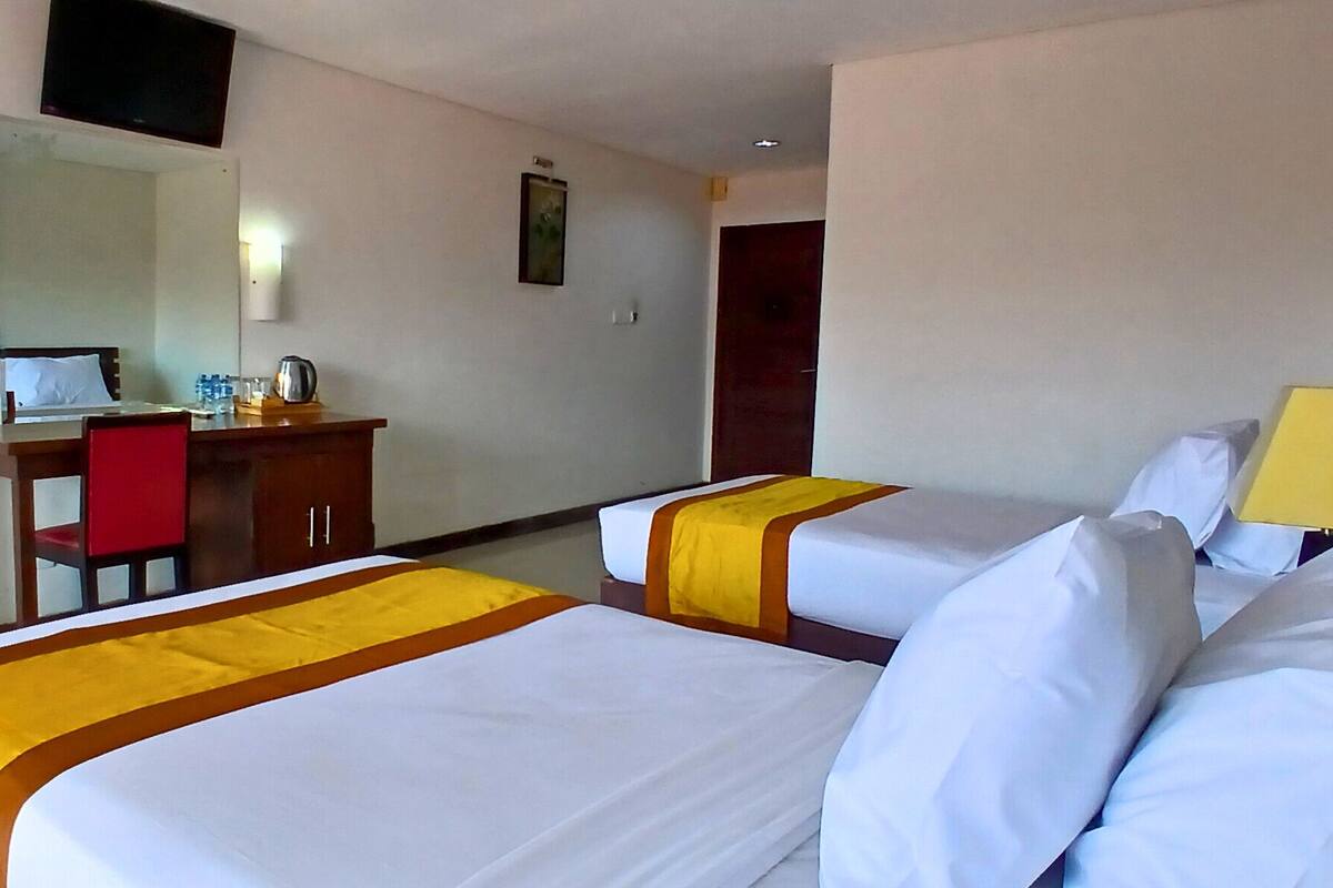Une chambre d’hôtel avec deux lits, un bureau, une chaise et un miroir.