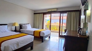 A hotel room with two beds, a desk, a lamp, and a view of the outdoors through a sliding door. - Nirmala Hotel and Convention Centre (Denpasar)