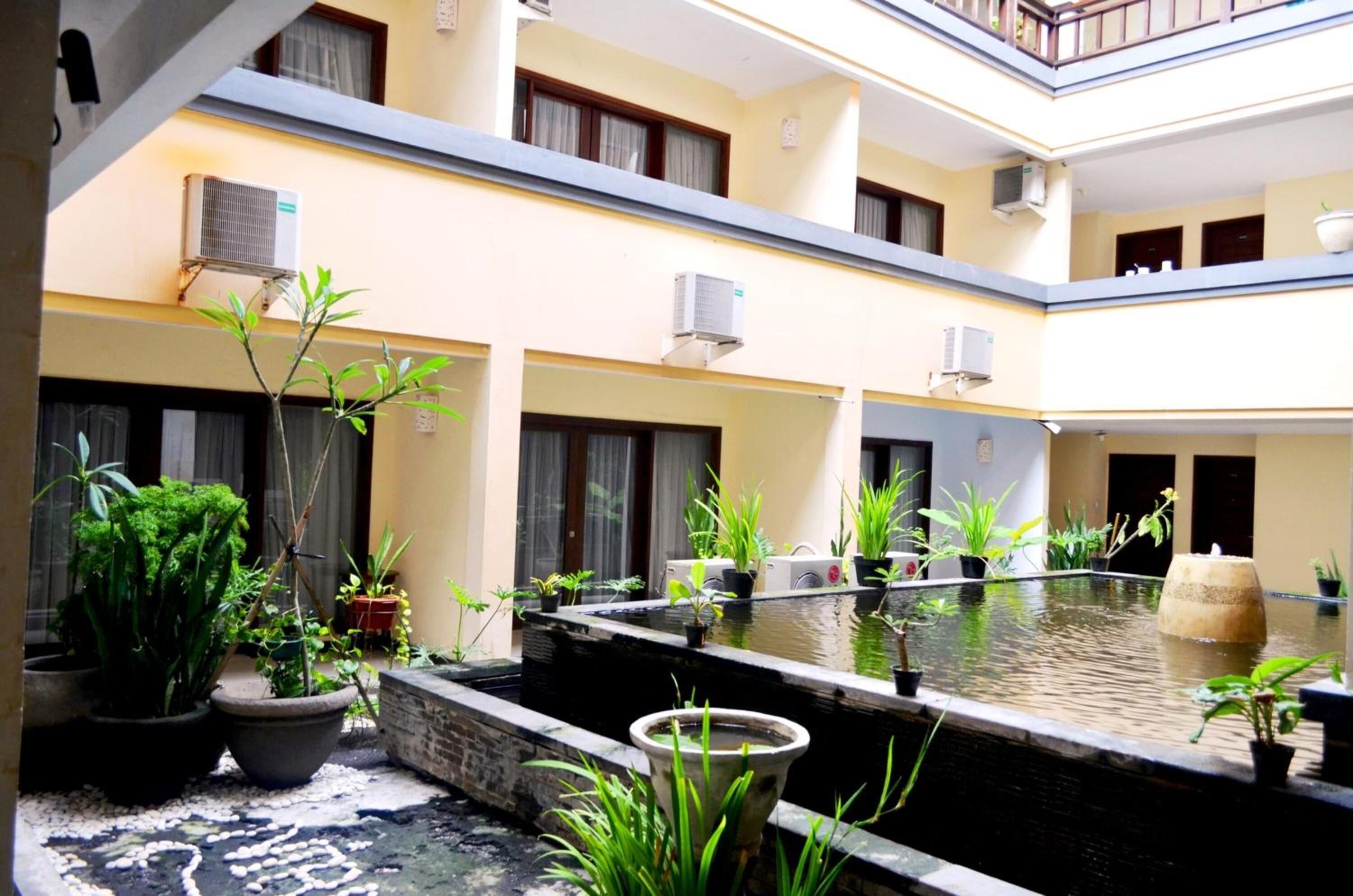 A multi-level courtyard with potted plants, a small water feature, and air conditioning units.