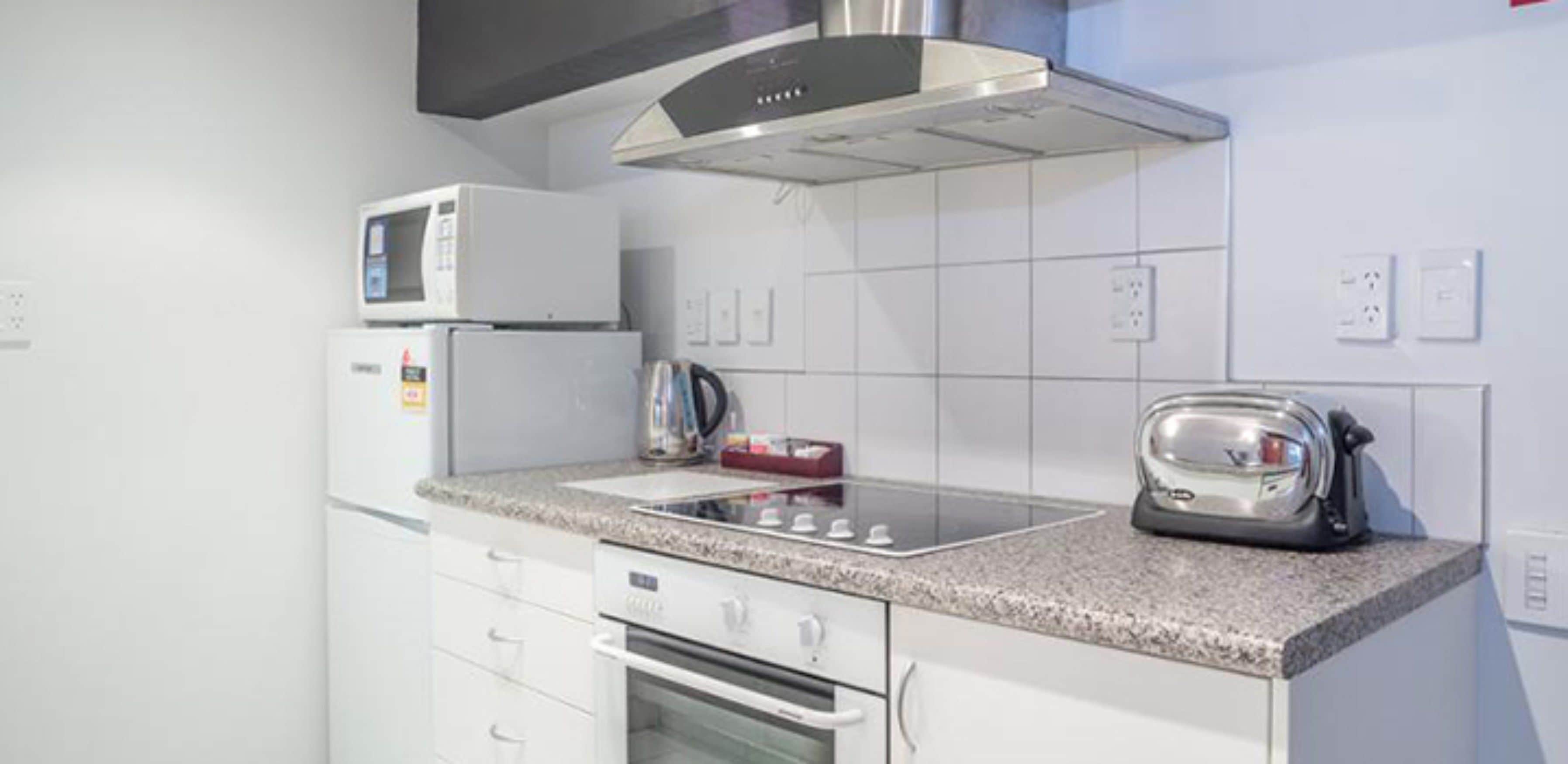 A modern kitchen with white cabinets, a built-in microwave, a toaster, and a gas stove.
