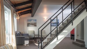 A modern living room with a staircase, a sofa, and two armchairs. - Willis Village (Wellington)
