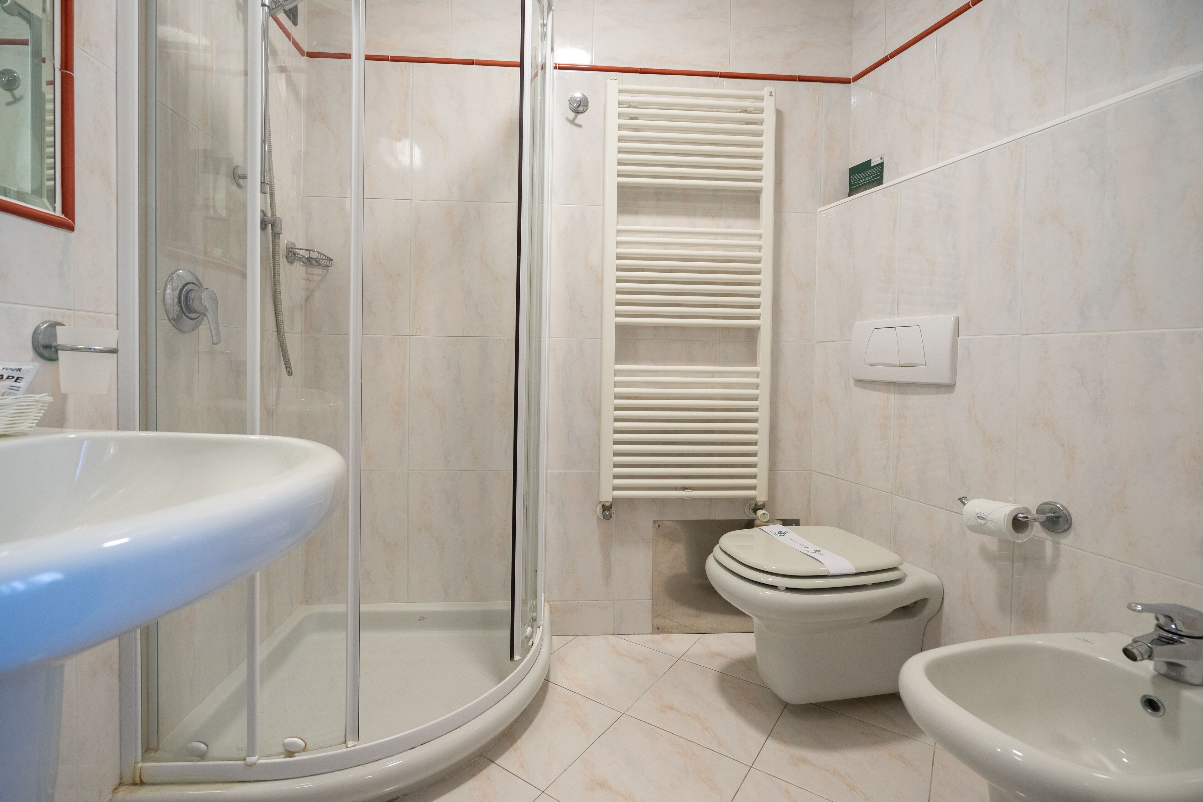 Un baño con ducha de vidrio, inodoro, bidé y lavamanos.