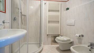 Un baño con ducha de vidrio, inodoro, bidé y lavamanos.