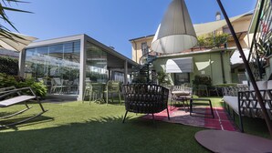 An outdoor seating area with a glass enclosure, a hanging lamp, and a red rug. - Hotel Bernardino (Lucca)