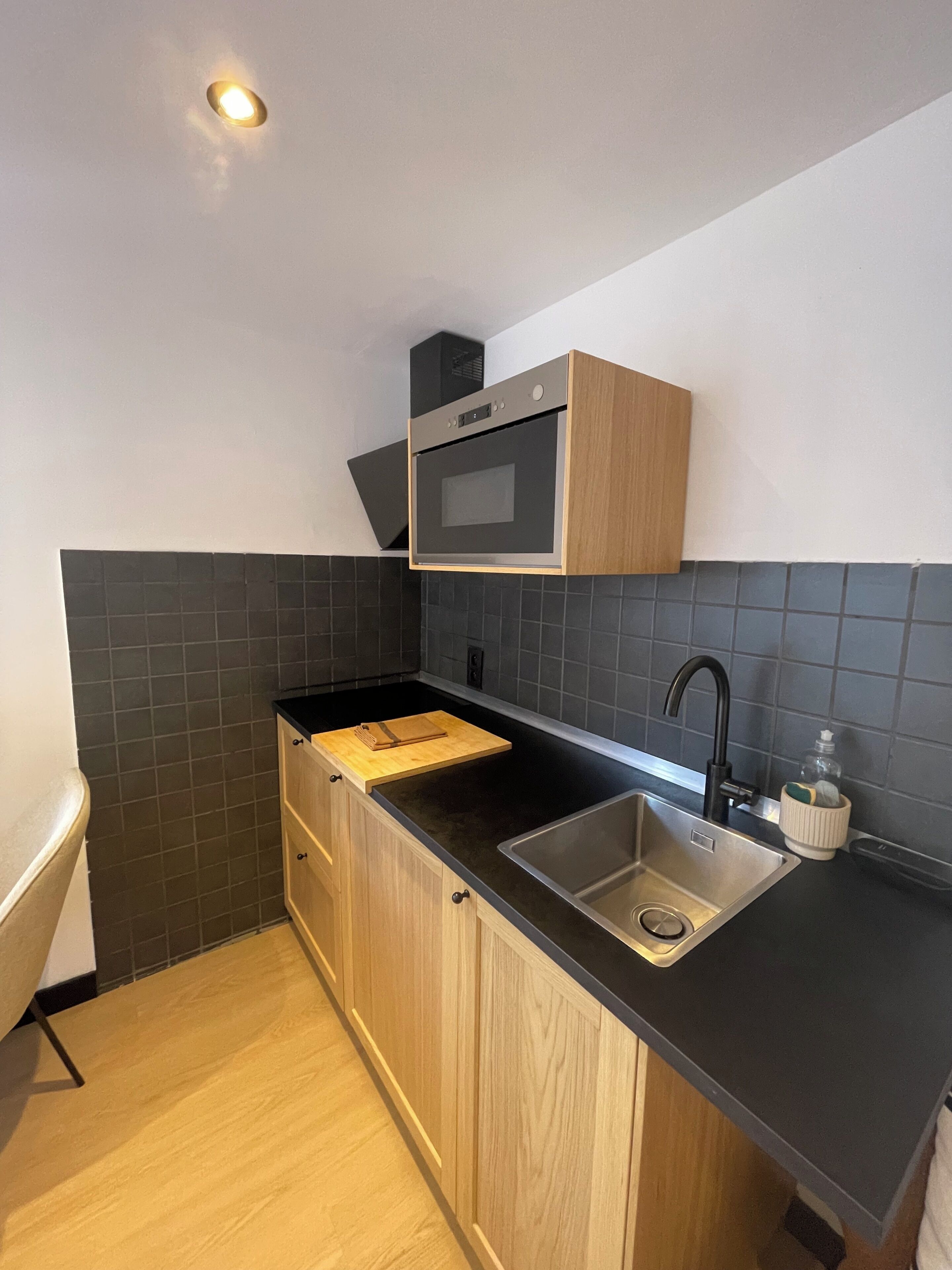 Een moderne keuken met een inbouwoven, een spoelbak en houten keukenkastjes.