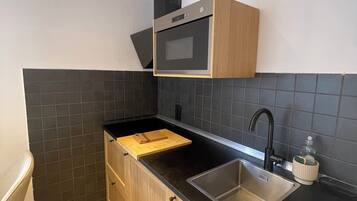 Een moderne keuken met een inbouwoven, een spoelbak en houten keukenkastjes.