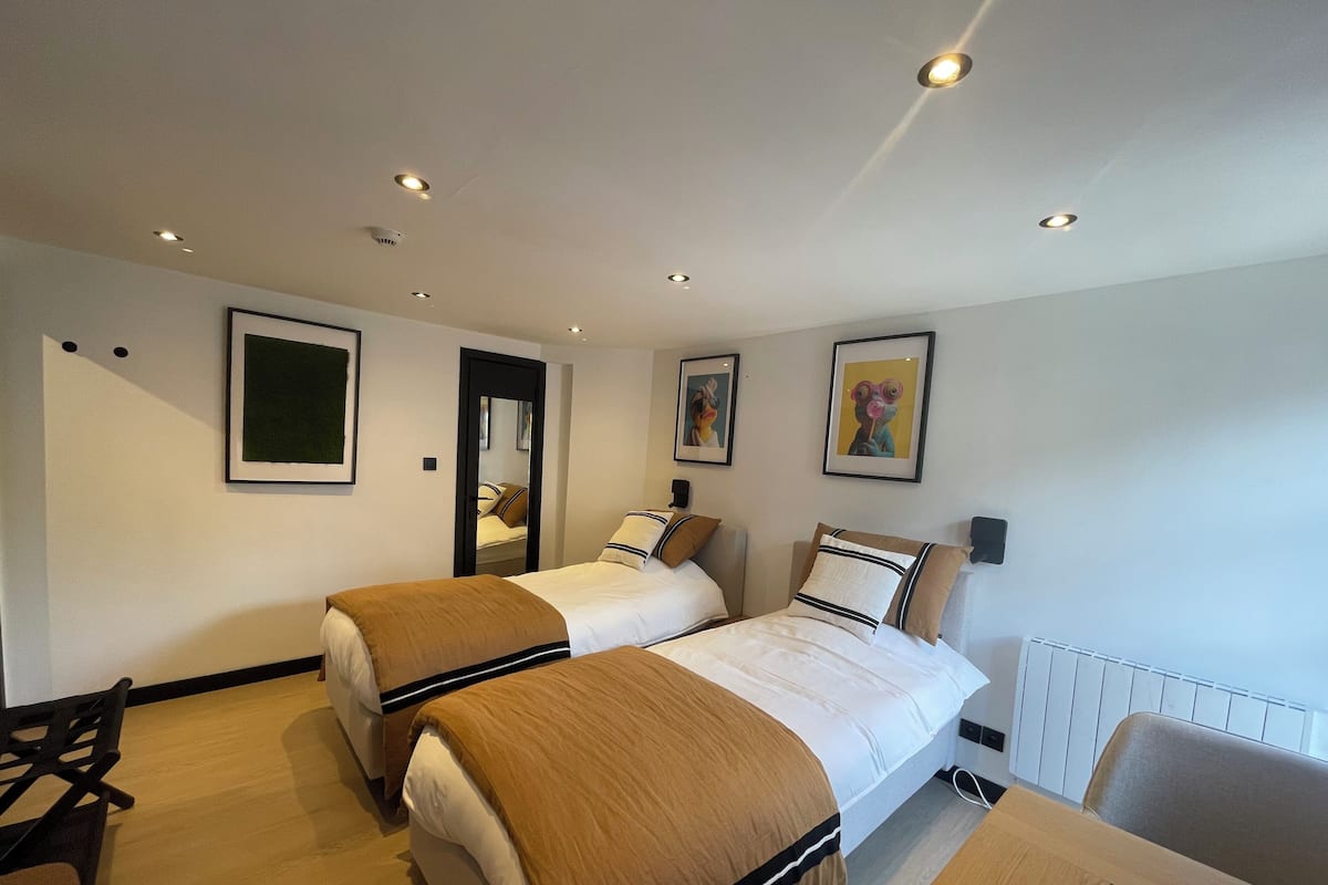 Habitación de hotel con dos camas, un escritorio, una silla y un radiador.