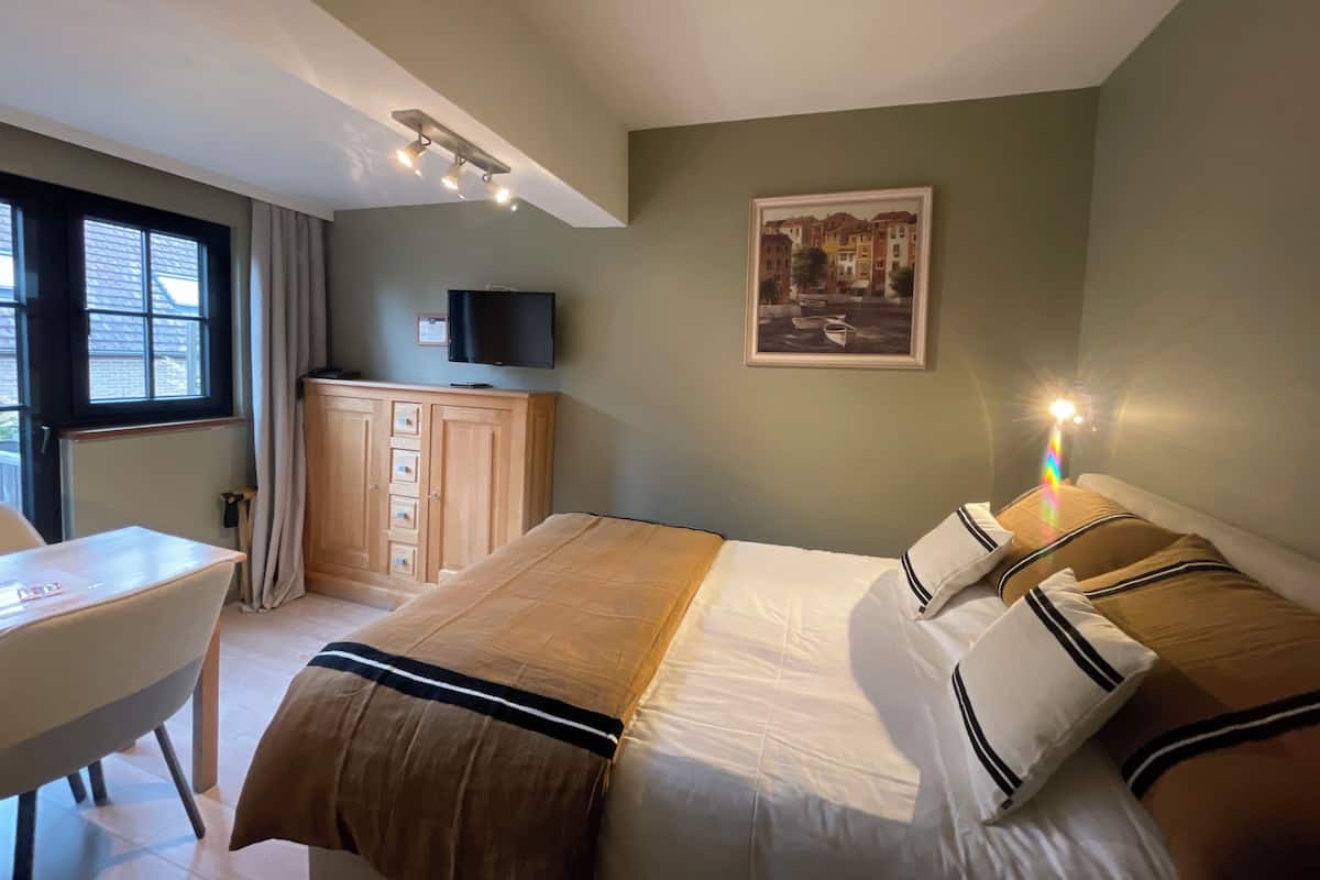 Una habitación de hotel con una cama, un escritorio, un televisor y una ventana.