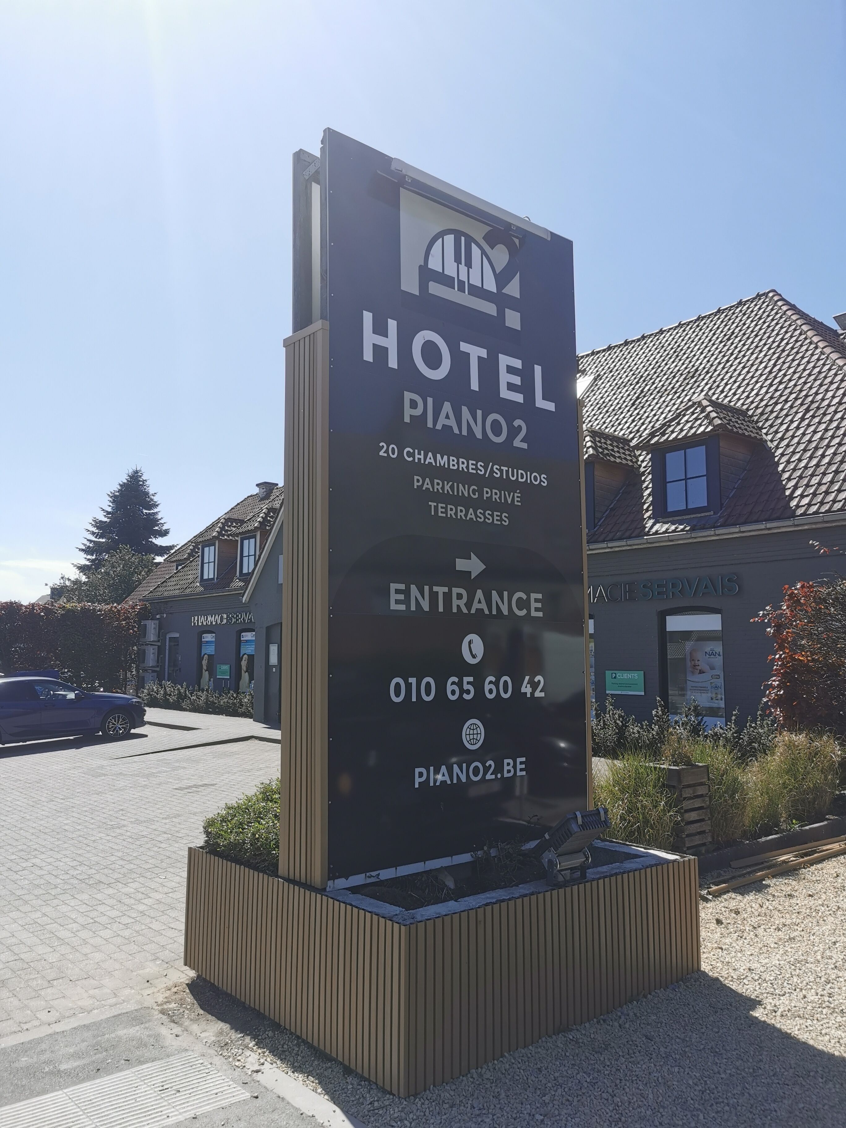 Une enseigne d’hôtel indiquant « HÔTEL PIANO2 » et fournissant les coordonnées.