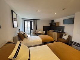 Habitación de hotel con dos camas, un escritorio, kitchenette y televisor.