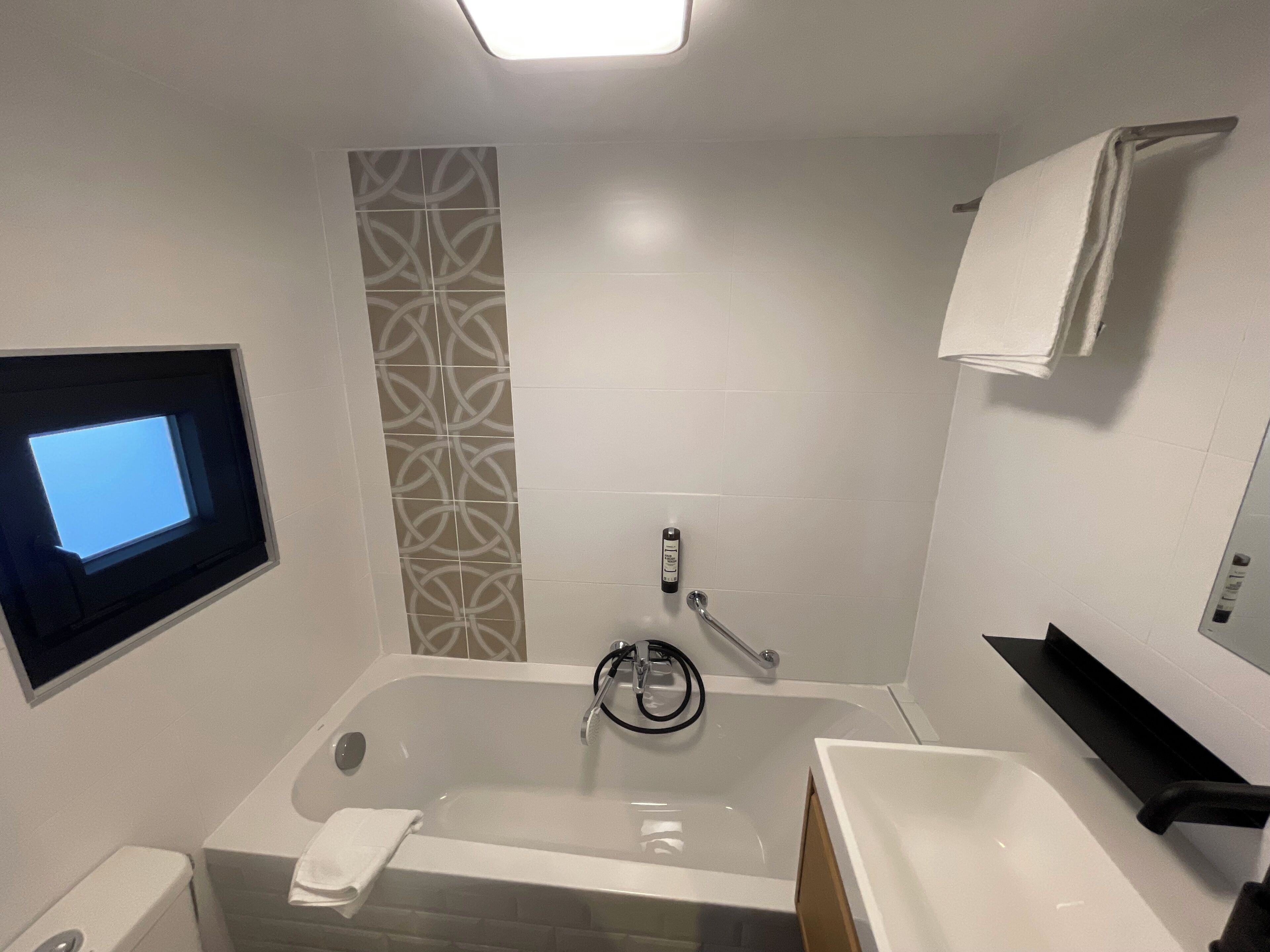 Uma casa de banho moderna com banheira, sanita, lavatório e zona de duche.