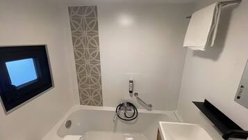 Uma casa de banho moderna com banheira, sanita, lavatório e zona de duche.