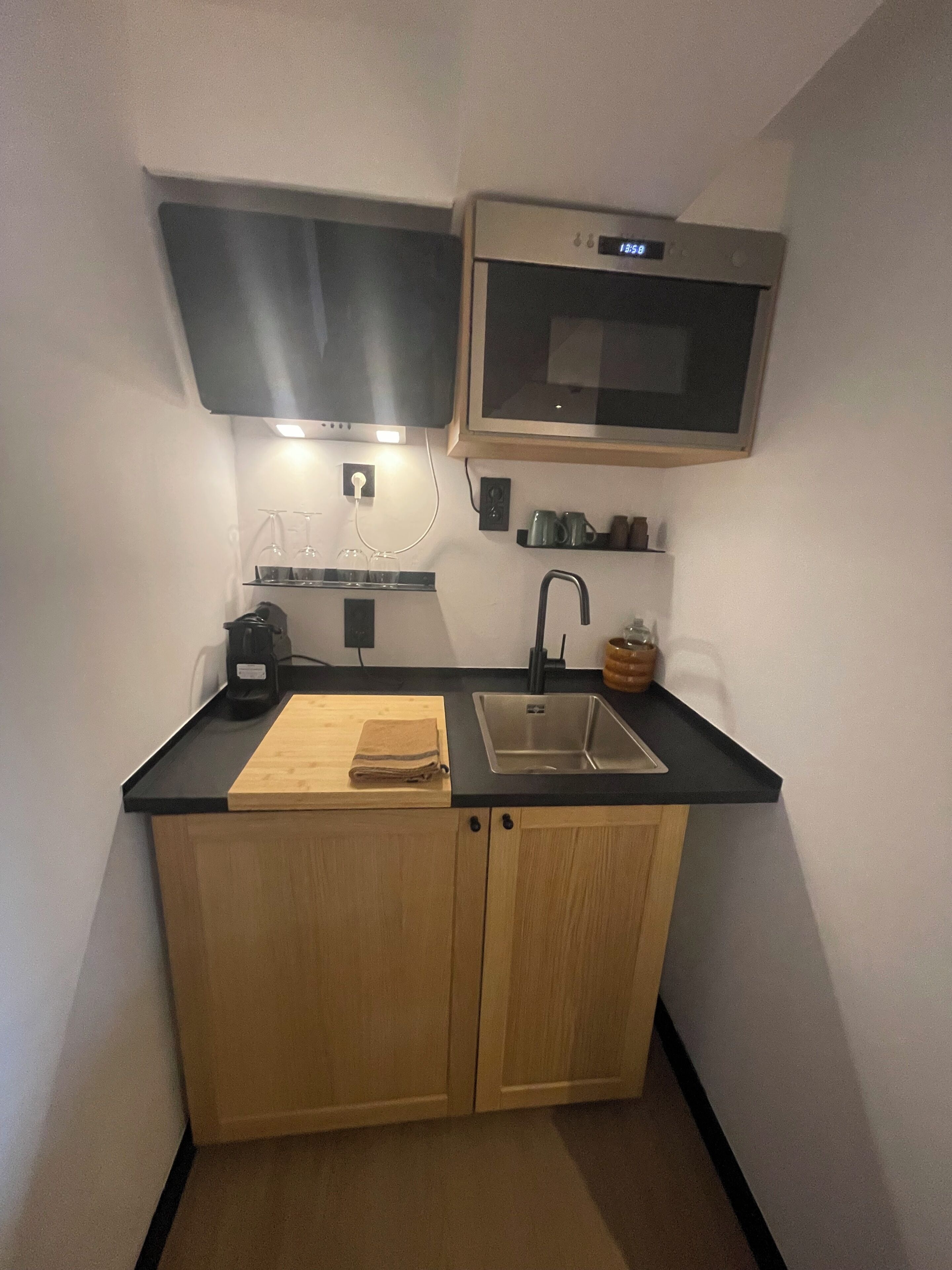 A compact kitchen with a microwave, sink, and wooden cabinets.