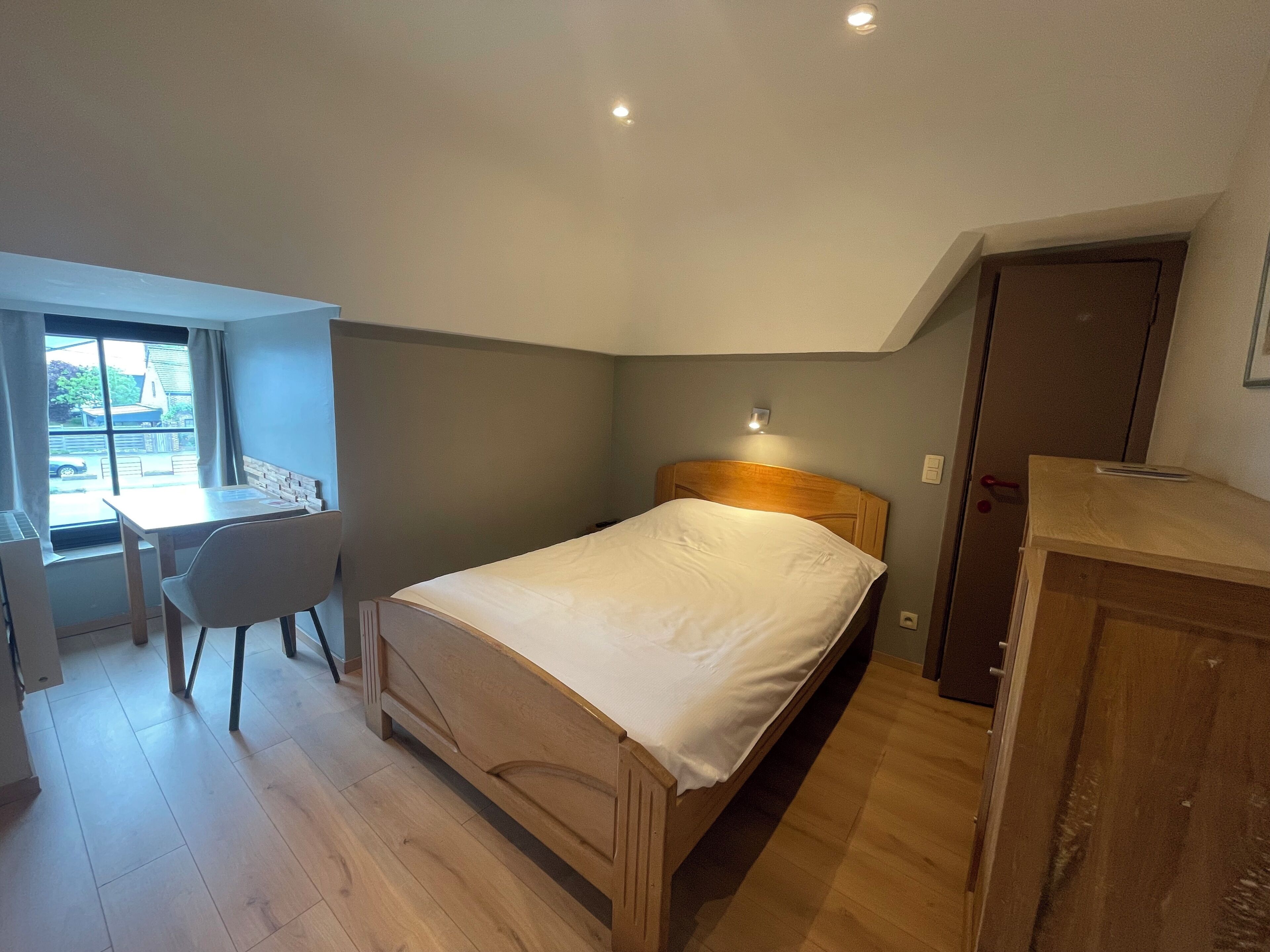 A bedroom with a wooden bed, a desk, and a chair.